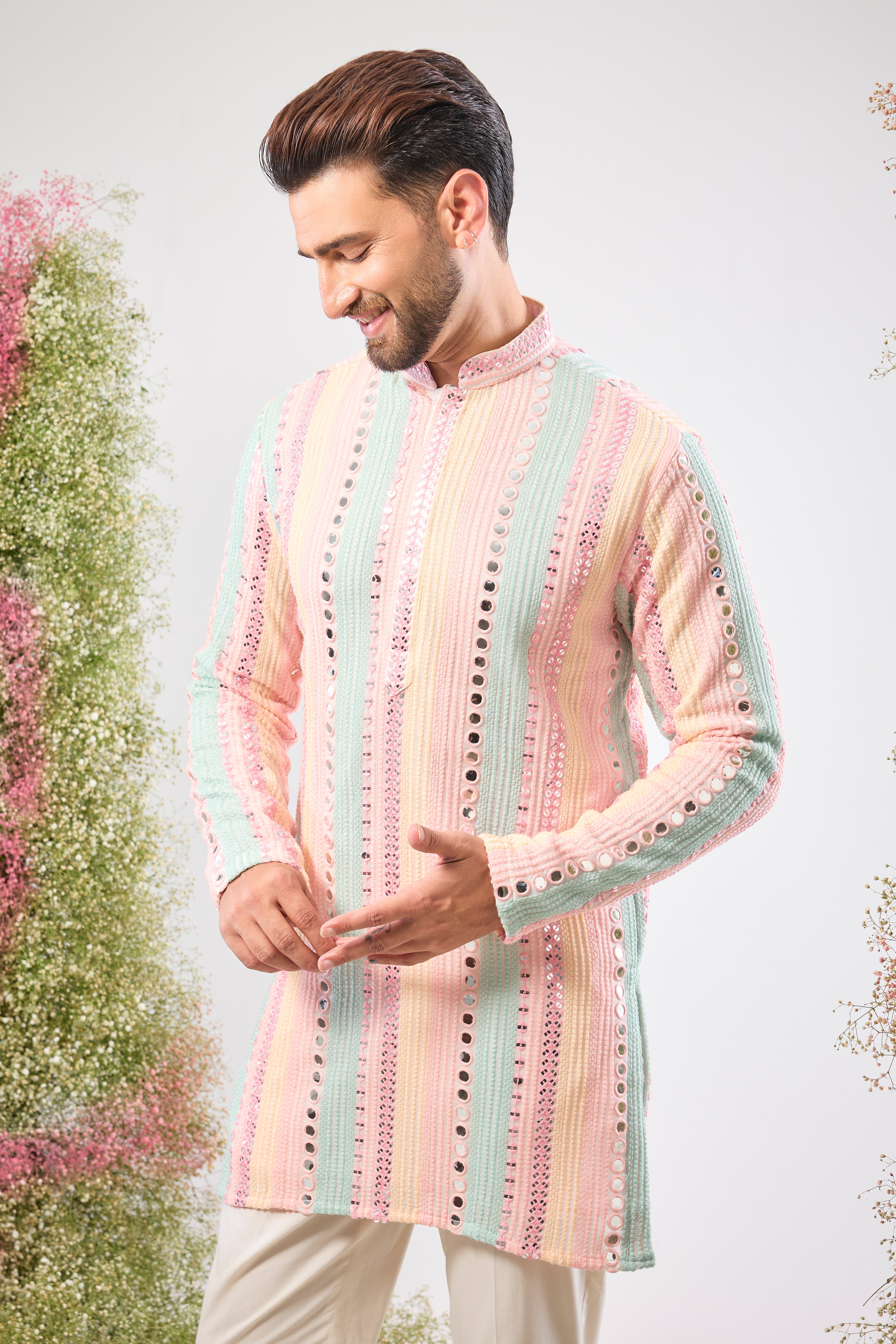 This Short Mirror Work Kurta showcases structured Pintucks Style Stripes filled with rich Multi-coloured Thread work, subtly enhanced by Delicate Sequin Work. The combination is utterly magical, offering a sophisticated yet joyful aesthetic.