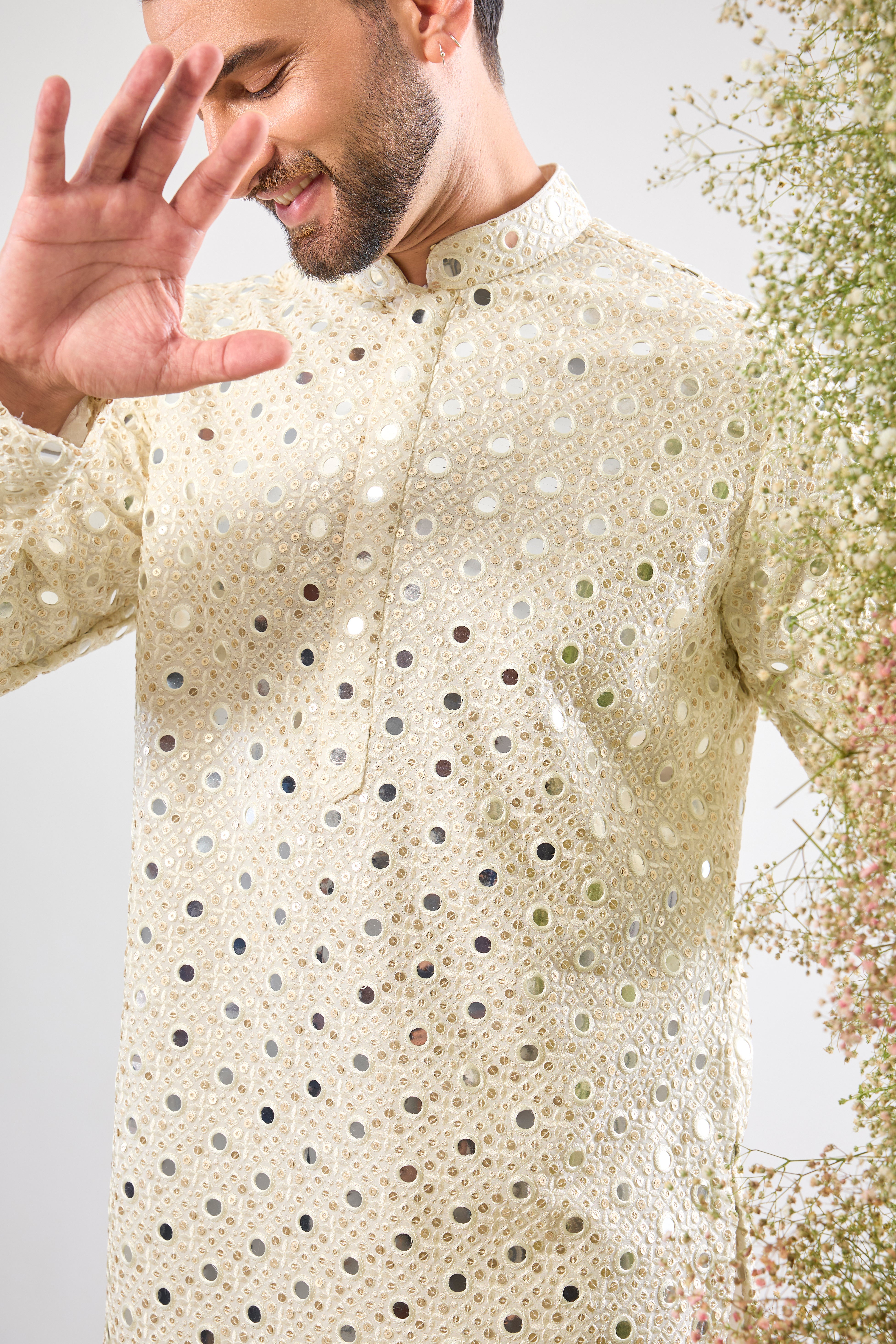 his White Short Mirror Work Kurta showcases the weight and brilliance of Detailed Heavy Sequin Work, providing a richly textured, luminous surface. The pristine white colour enhances the sparkle, ensuring a truly show-stopping look
