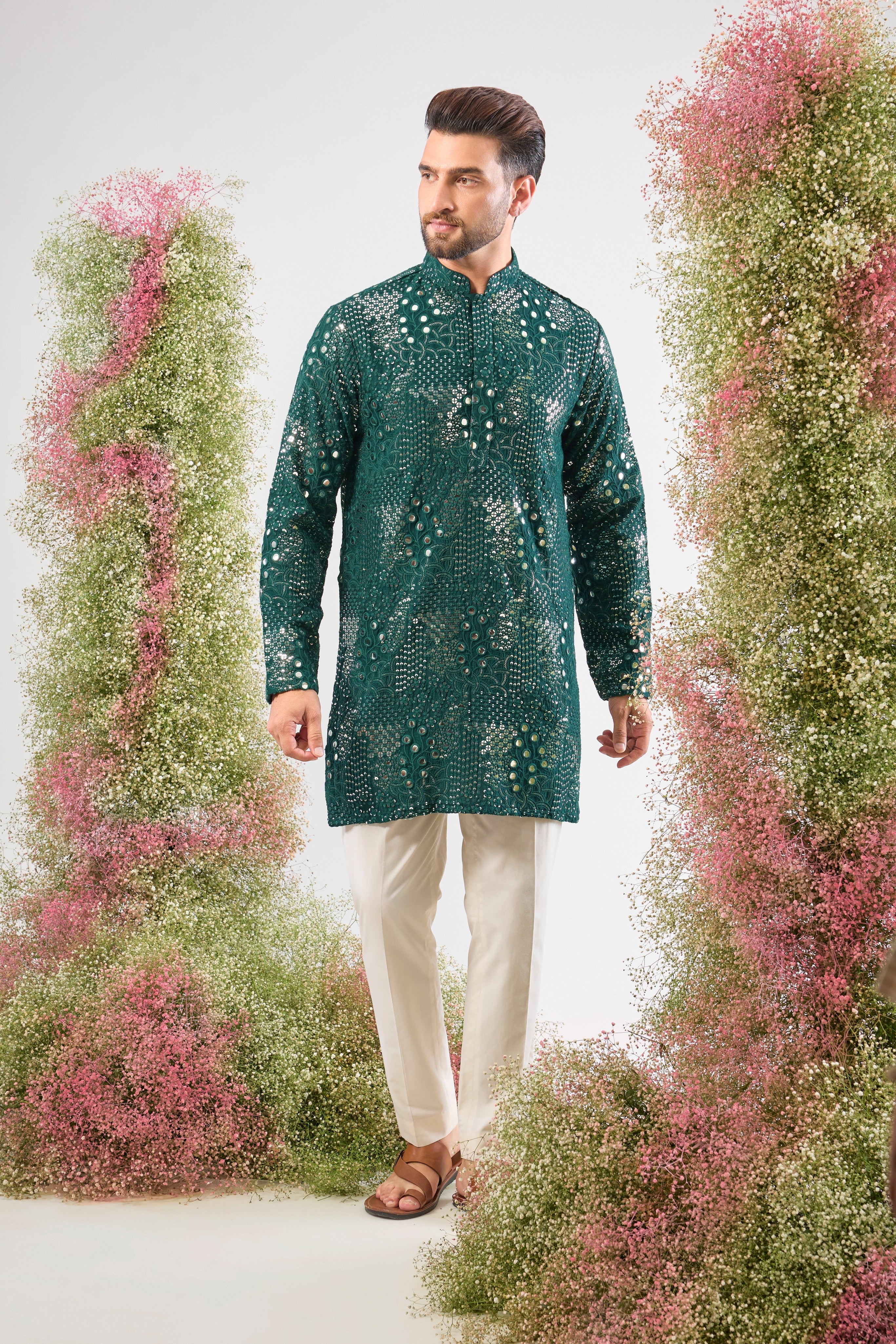 This Bottle Green Short Mirror Work Kurta showcases Intricate Sequin Work arranged in a beautiful Floral Pattern. The dense sequin detailing ensures a luminous, unforgettable texture, making it an ideal choice for a sophisticated, festive look.