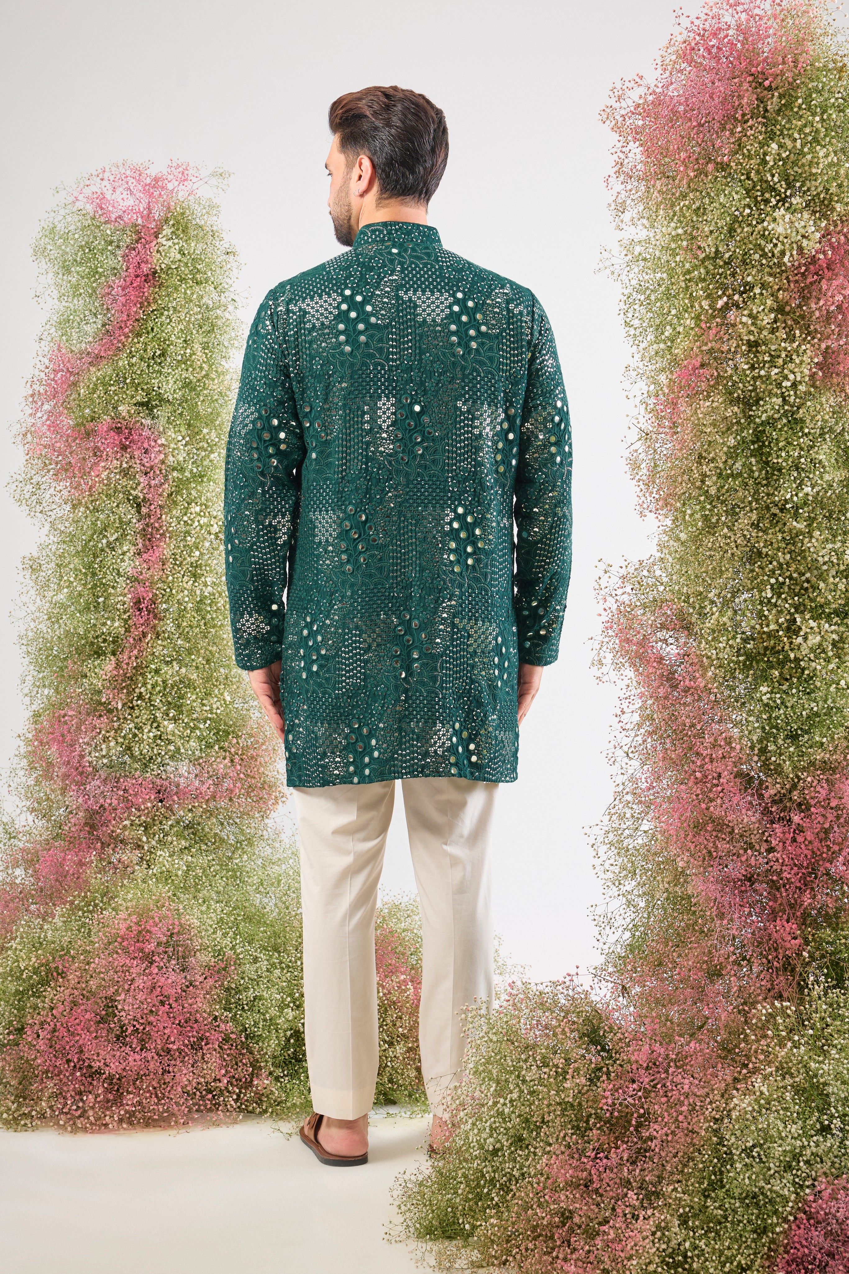 This Bottle Green Short Mirror Work Kurta showcases Intricate Sequin Work arranged in a beautiful Floral Pattern. The dense sequin detailing ensures a luminous, unforgettable texture, making it an ideal choice for a sophisticated, festive look.