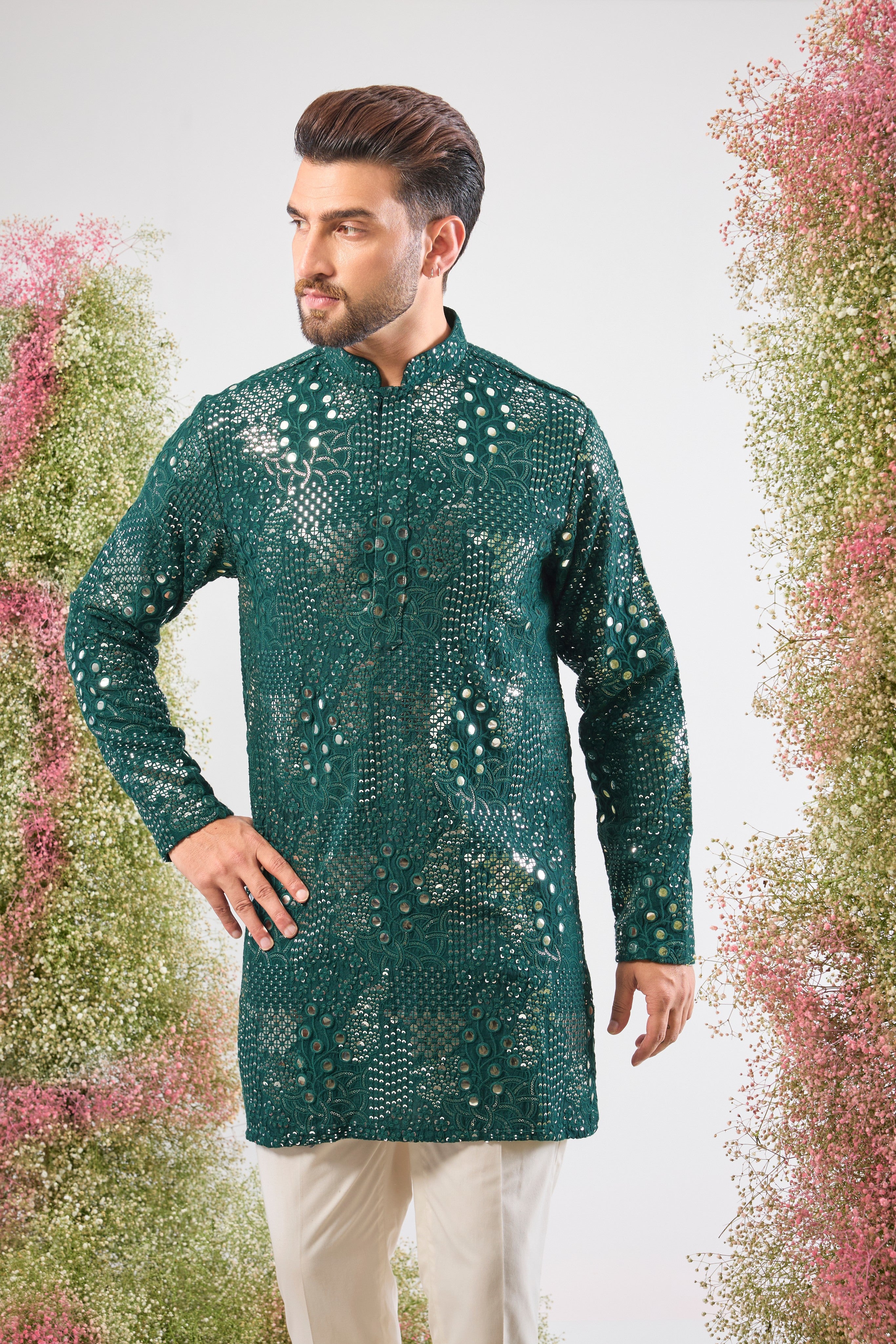 This Bottle Green Short Mirror Work Kurta showcases Intricate Sequin Work arranged in a beautiful Floral Pattern. The dense sequin detailing ensures a luminous, unforgettable texture, making it an ideal choice for a sophisticated, festive look.