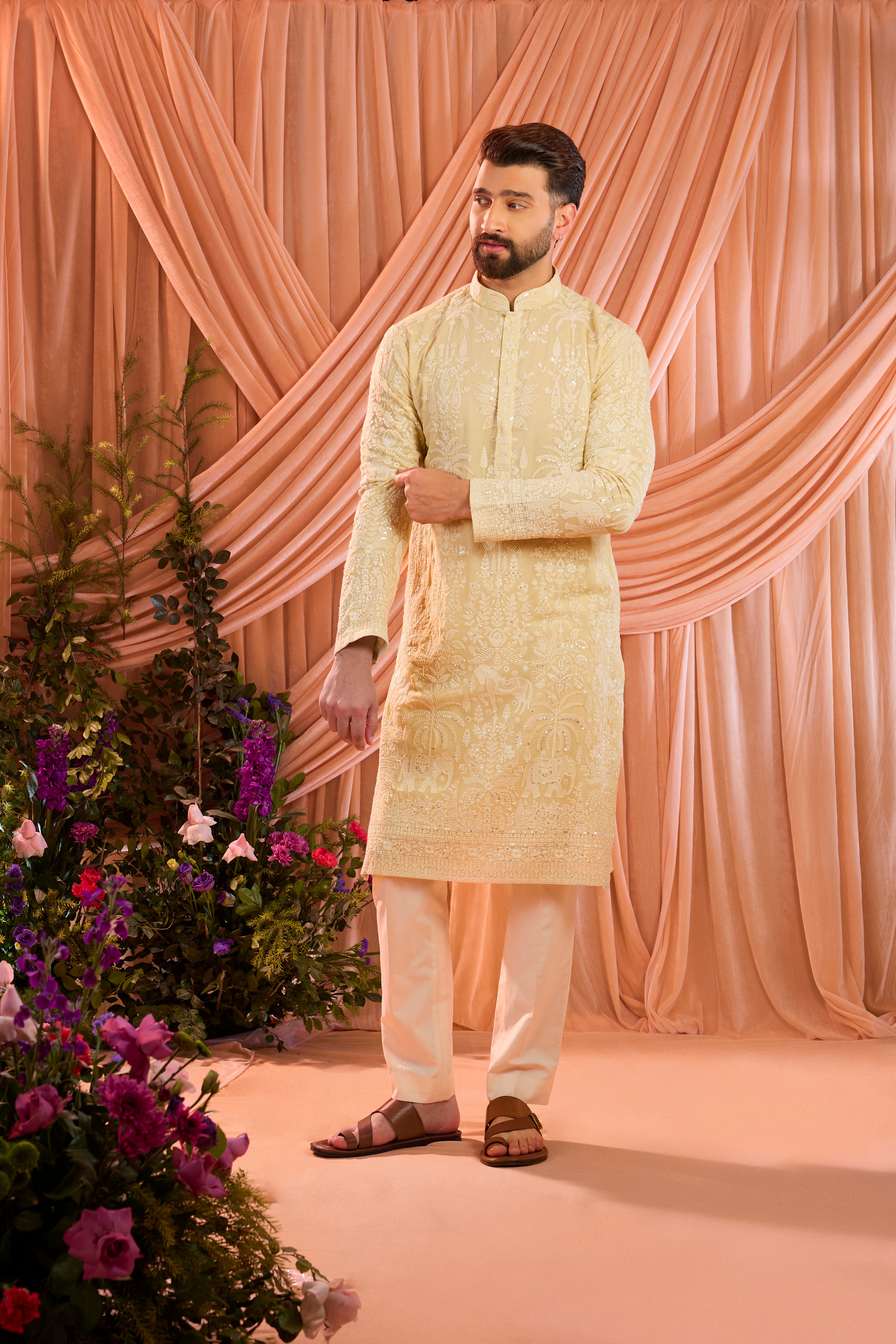 A pastel yellow  kurta illuminated with delicate sequins, brought to life by intricate flora and fauna embroidery.