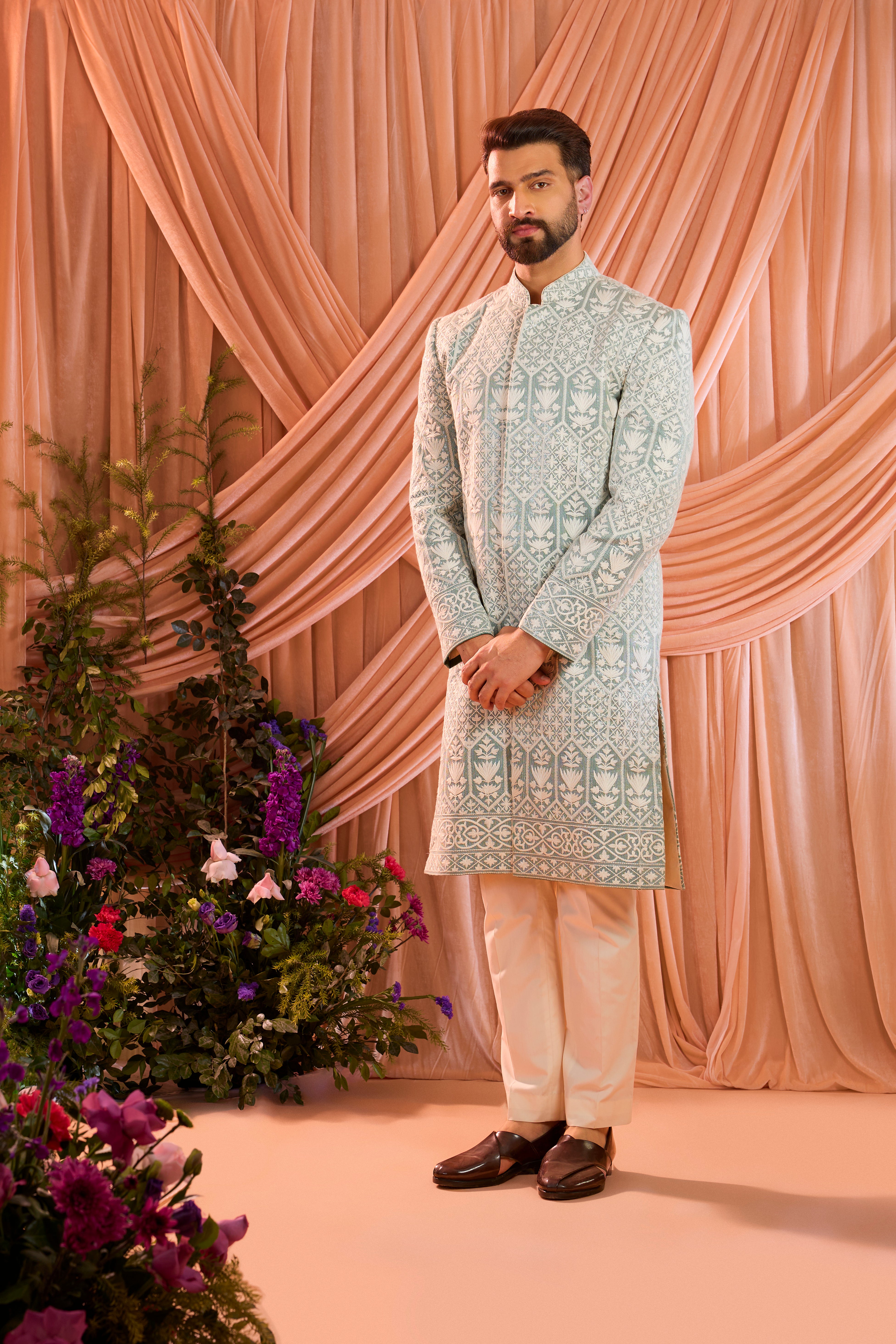 An aqua blue chikankari sherwani distinguished by heavy ivory threadwork and meticulously detailed sequin embellishment.