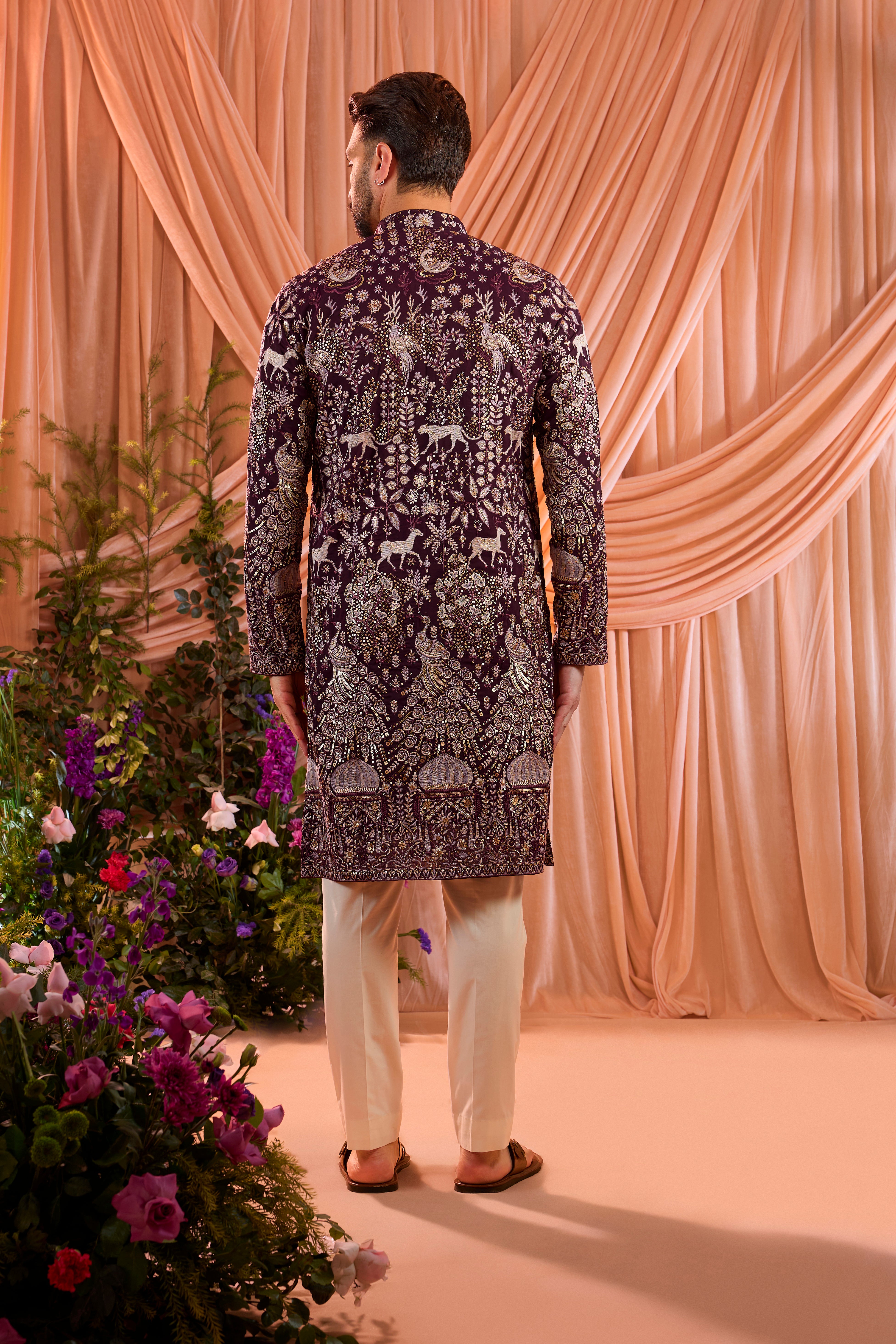 A wine royal-heritage  kurta adorned with detailed flora and fauna motifs and intricate darbar scenes.