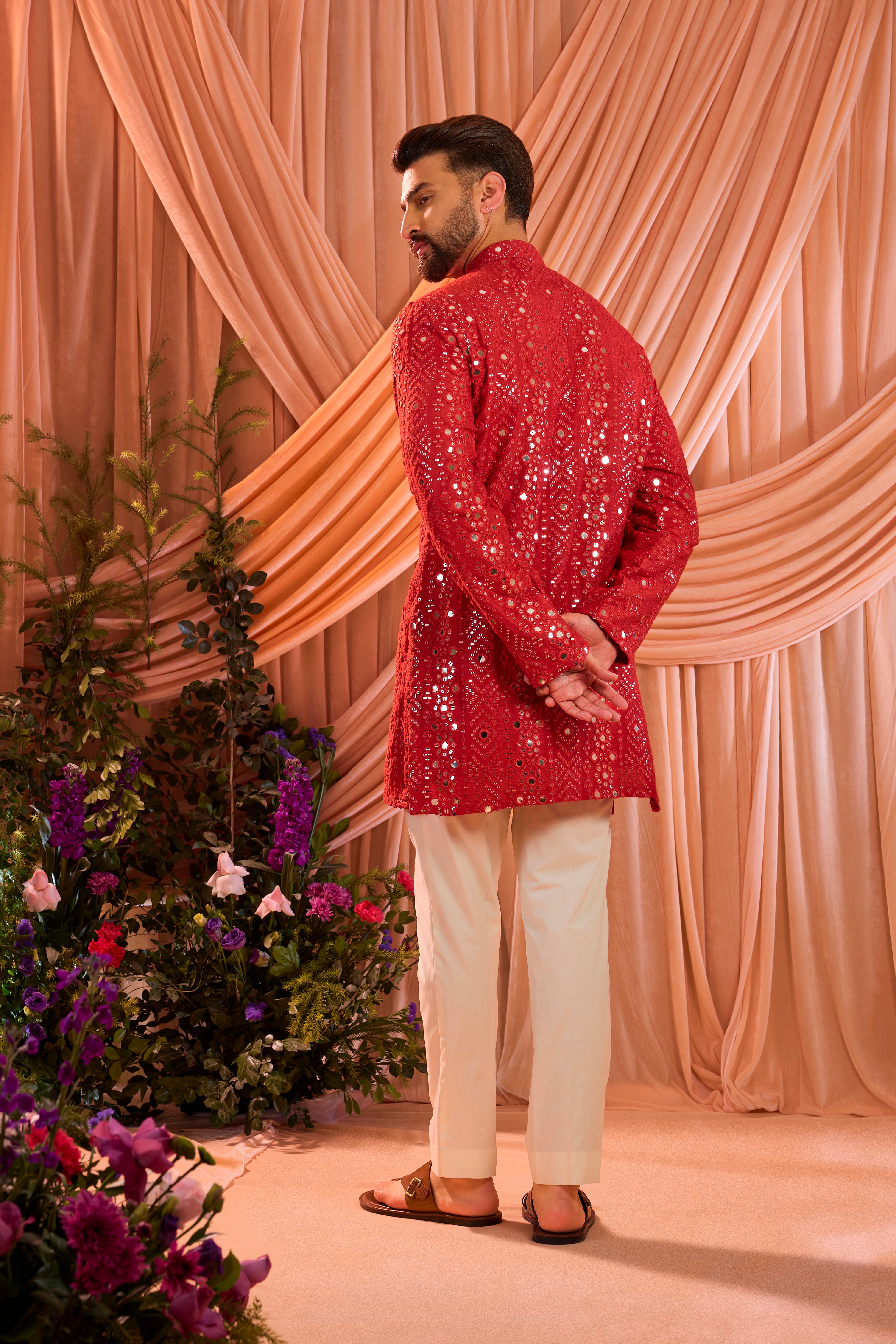 A signature red short kurta featuring mirror-inspired sequin work that recreates the brilliance of traditional mirror craftsmanship.