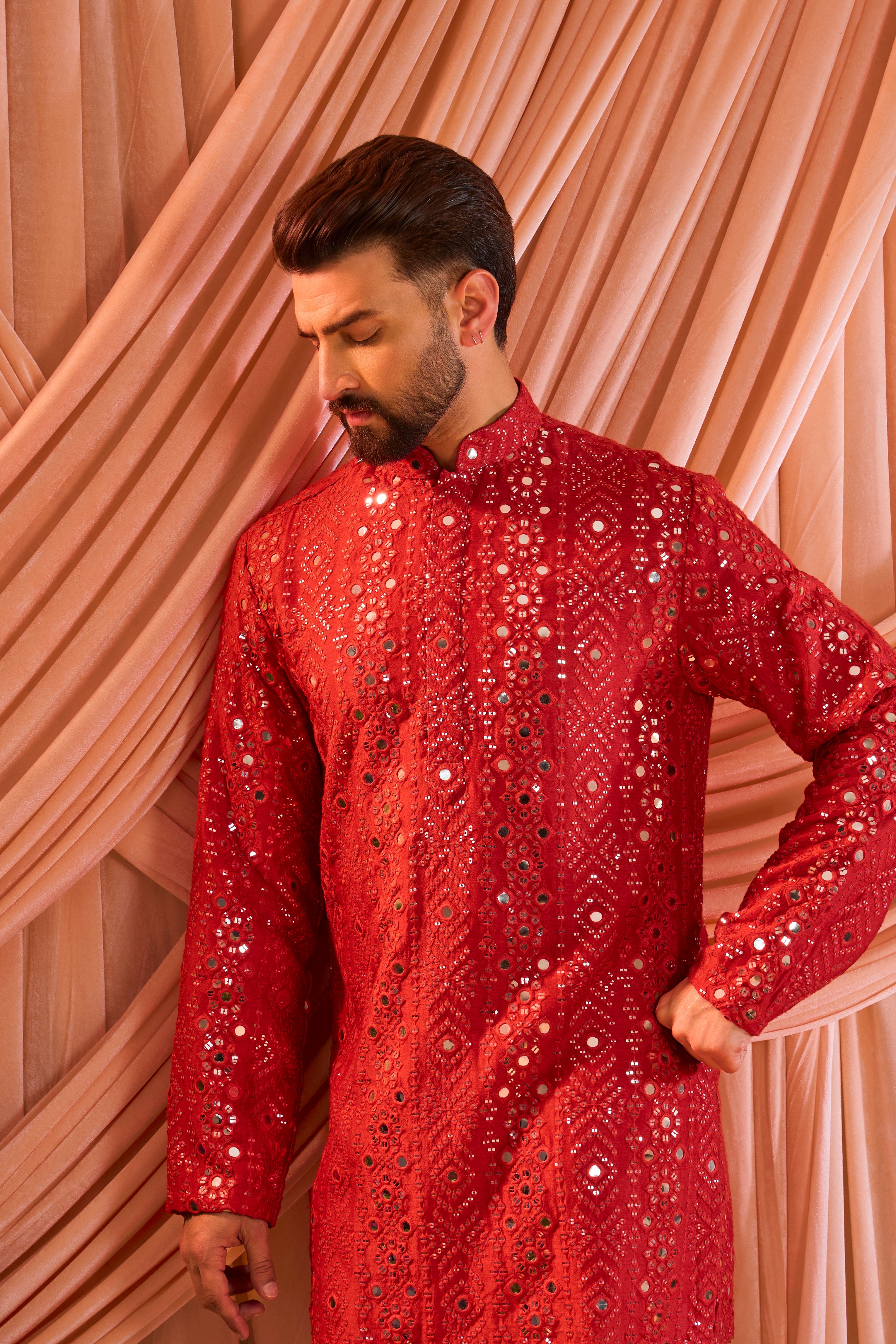 A signature red short kurta featuring mirror-inspired sequin work that recreates the brilliance of traditional mirror craftsmanship.