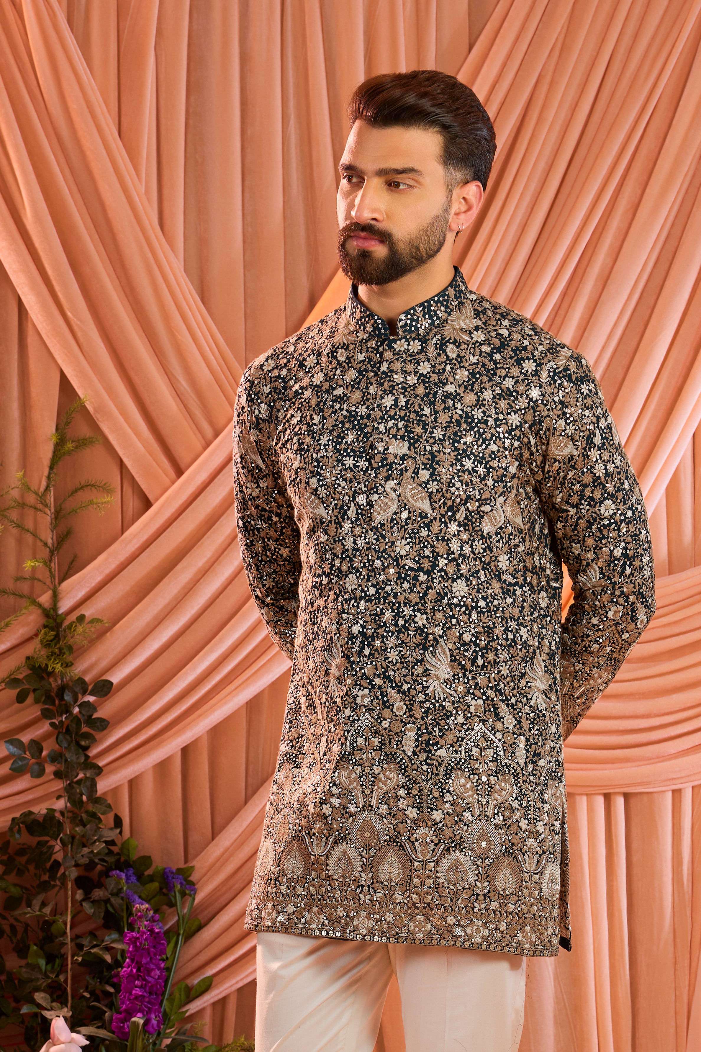 A teal short kurta adorned with intricate sequin embellishment, brought to life by detailed flora and fauna figures.