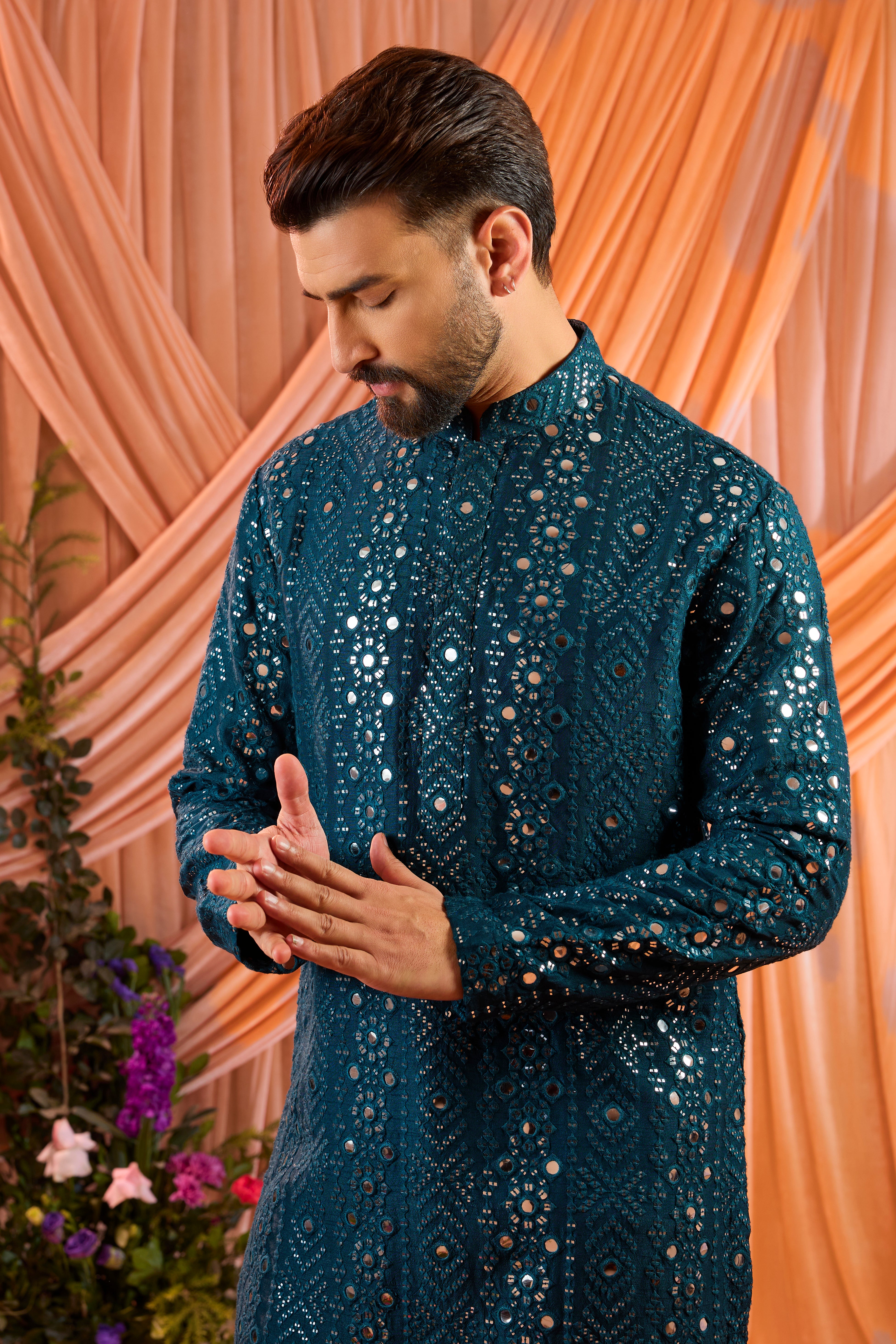 A signature teal short kurta featuring mirror-inspired sequin work that recreates the brilliance of traditional mirror craftsmanship. The refined surface detailing adds depth and controlled shimmer.