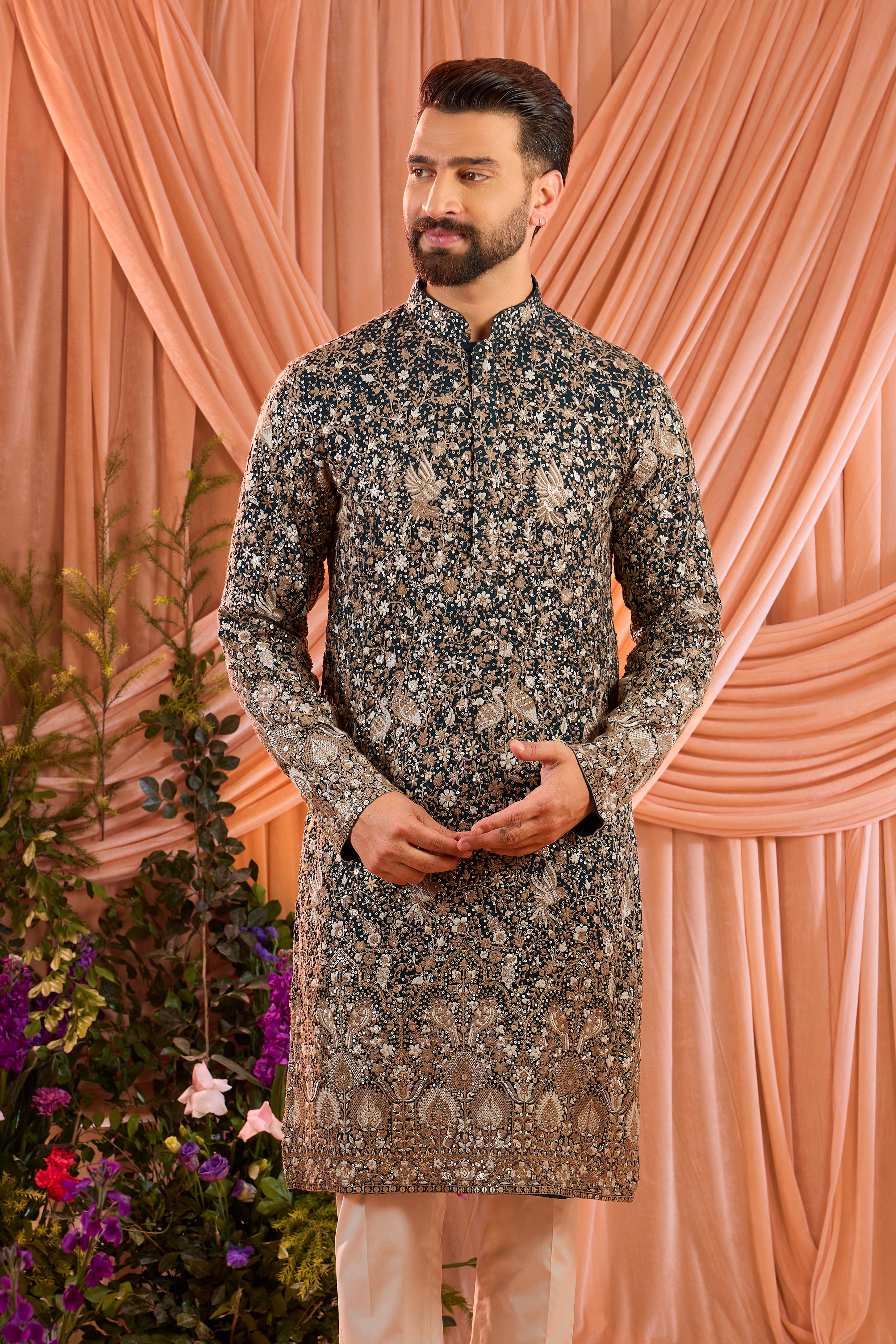 A teal long kurta adorned with intricate sequin embellishment, brought to life by detailed flora and fauna figures.