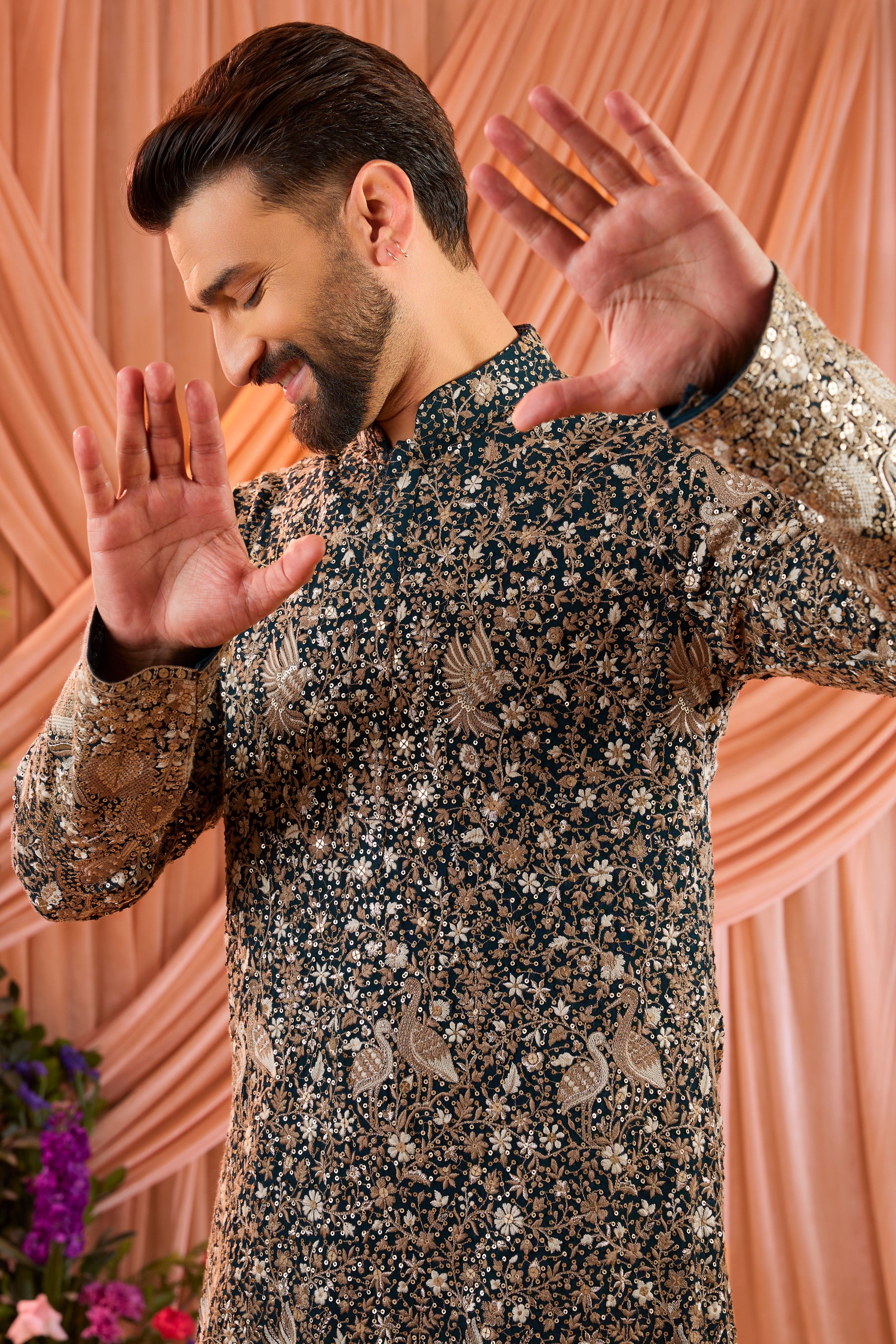 A teal long kurta adorned with intricate sequin embellishment, brought to life by detailed flora and fauna figures.