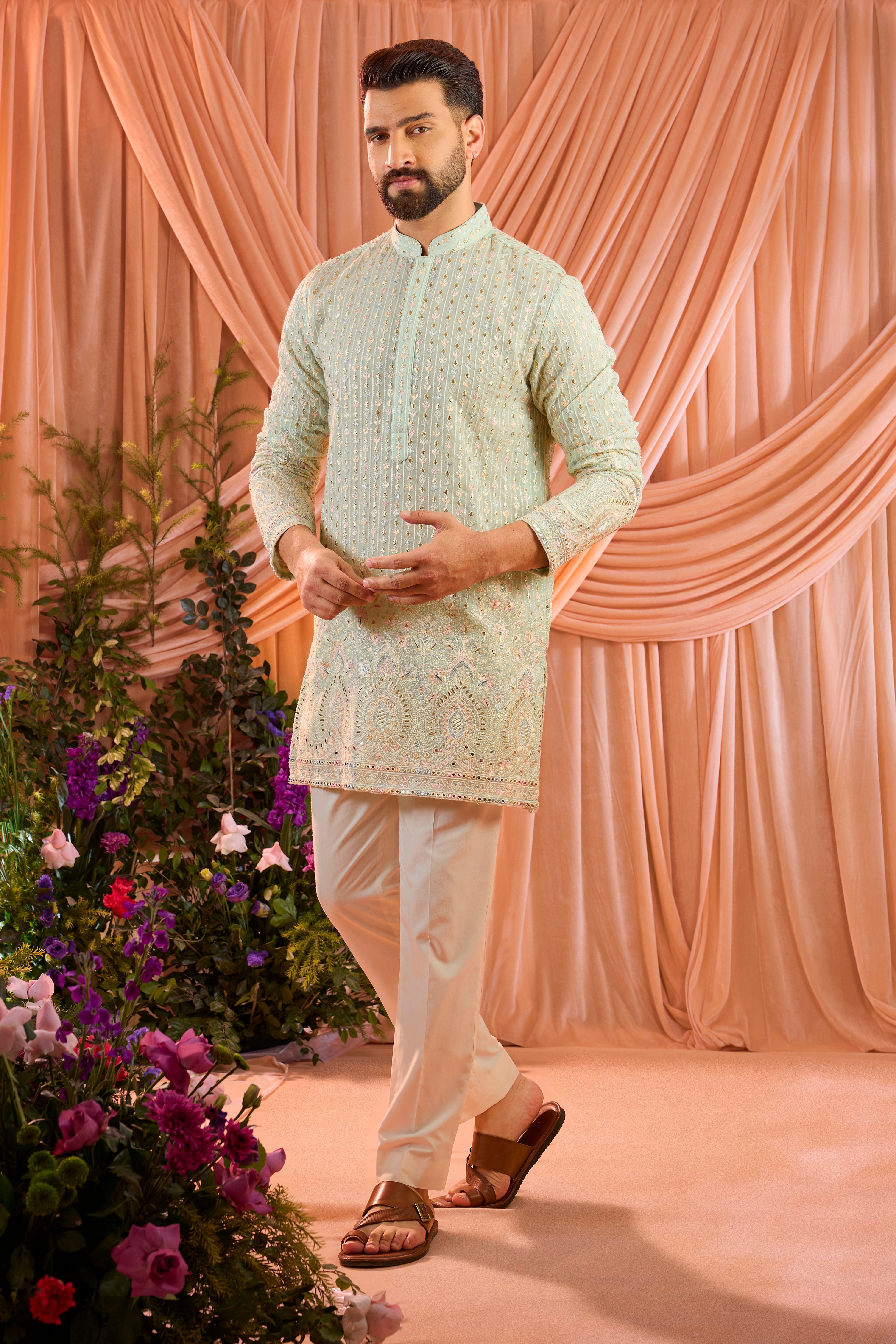 A aqua blue short kurta detailed with intricate multi-thread embroidery, enhanced by delicate sequins and subtle foil accents.