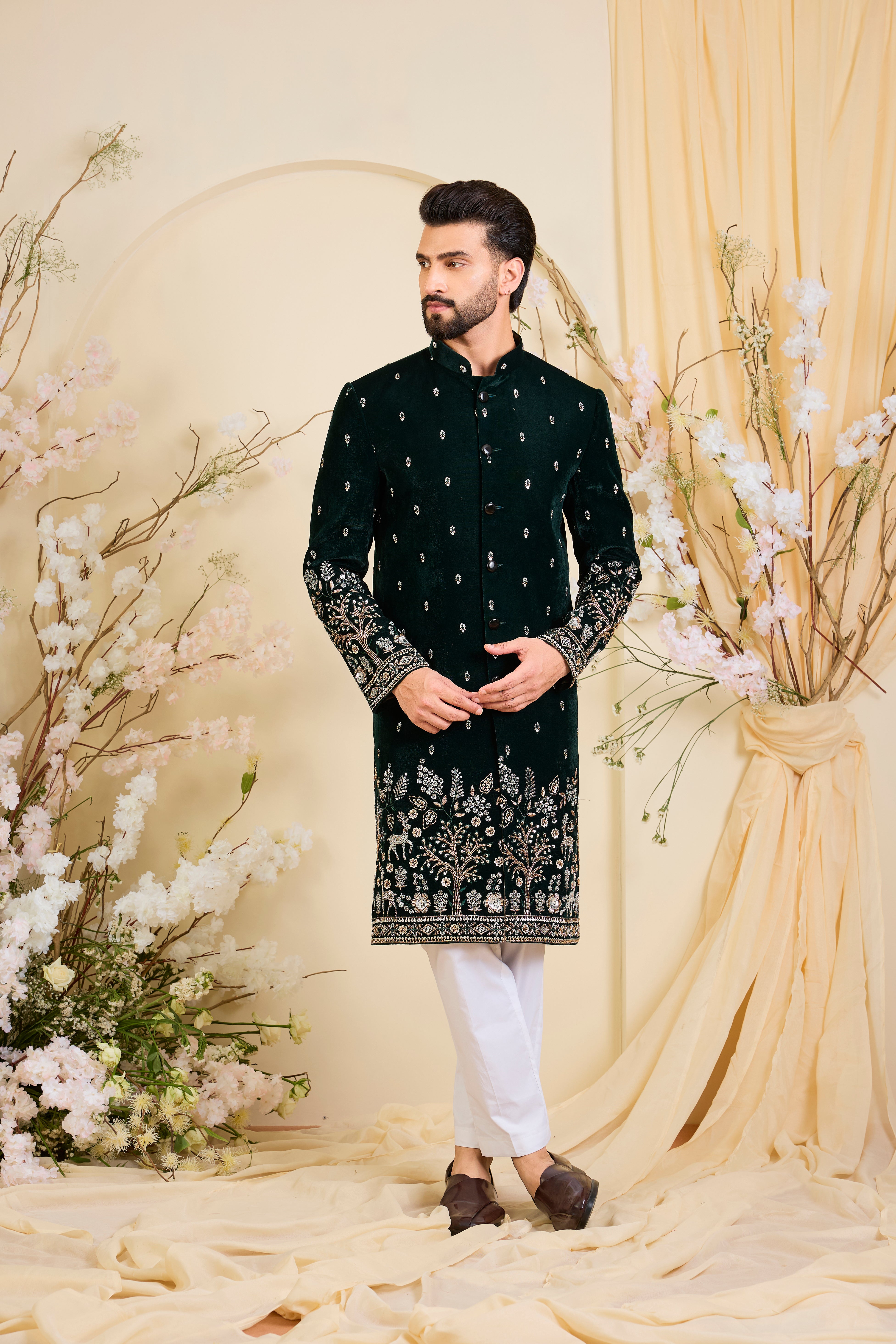An opulent bottle green sherwani, intricately hand-embroidered with dense cut dana work and elaborate flora-fauna motifs, exuding regal depth and grand sophistication.
