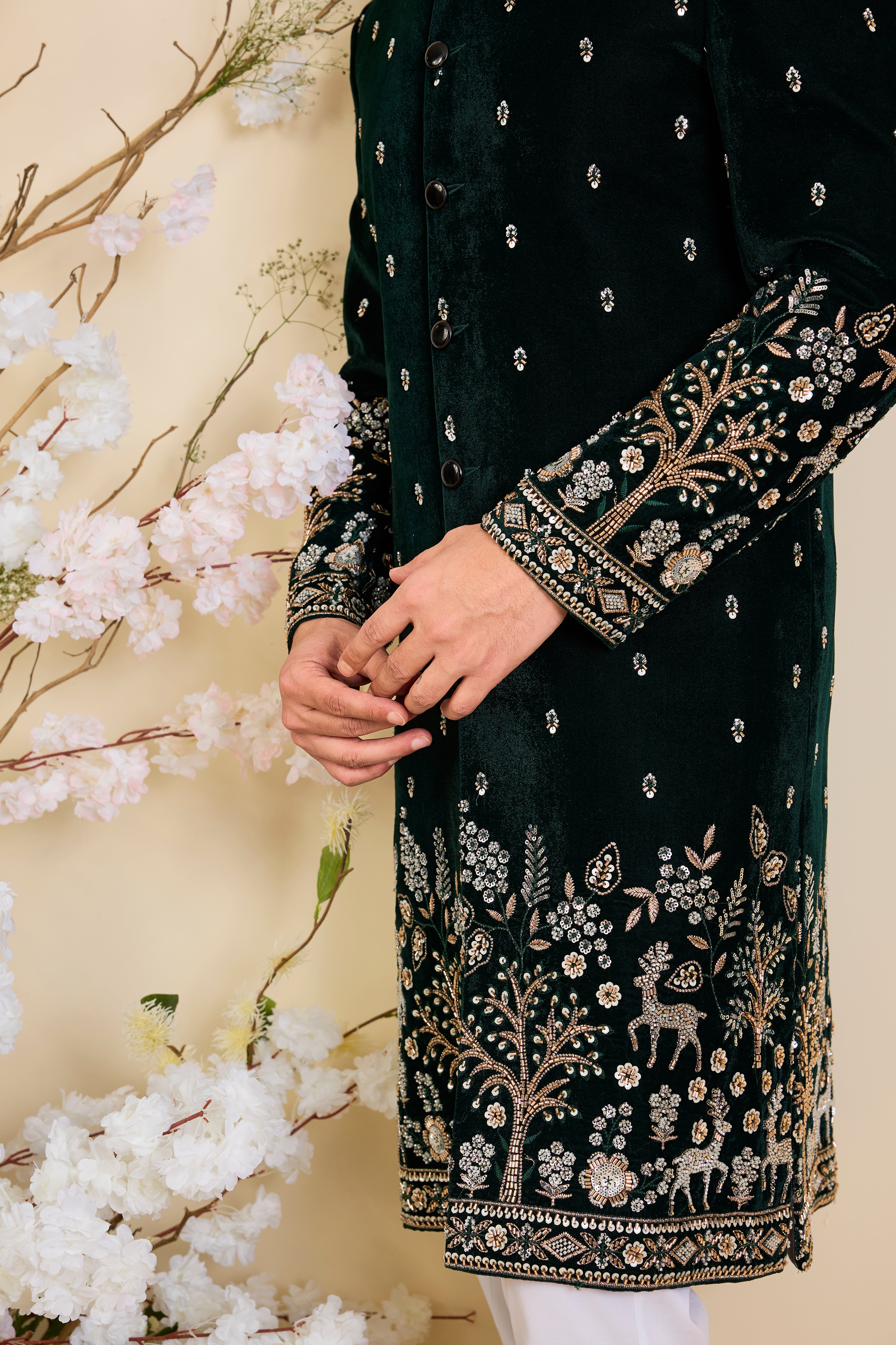 An opulent bottle green sherwani, intricately hand-embroidered with dense cut dana work and elaborate flora-fauna motifs, exuding regal depth and grand sophistication.