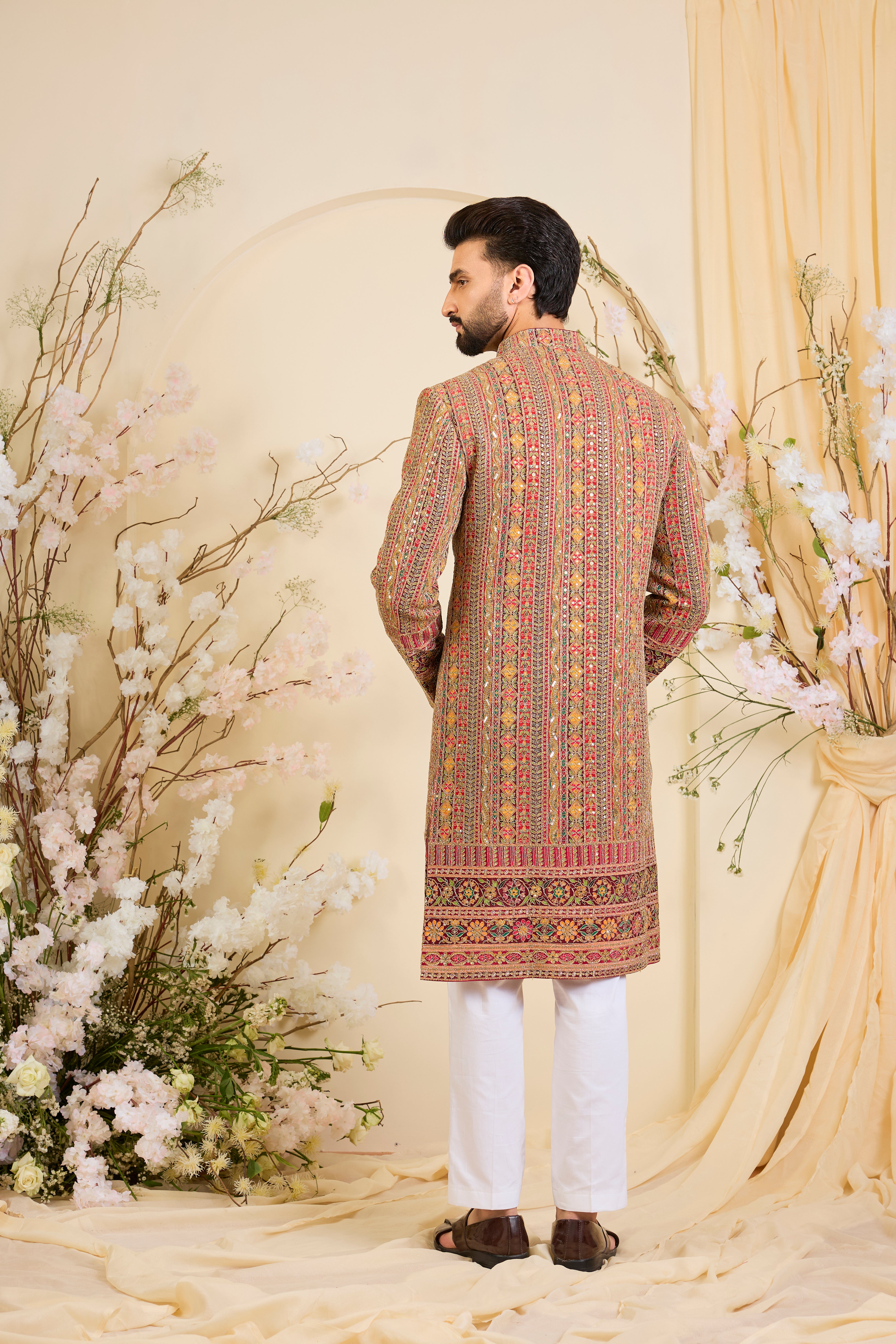 Pink base sherwani with heavy zari embroidery, intricate sequins, and multicolour prints, crafted for bold, opulent, statement-making occasions.