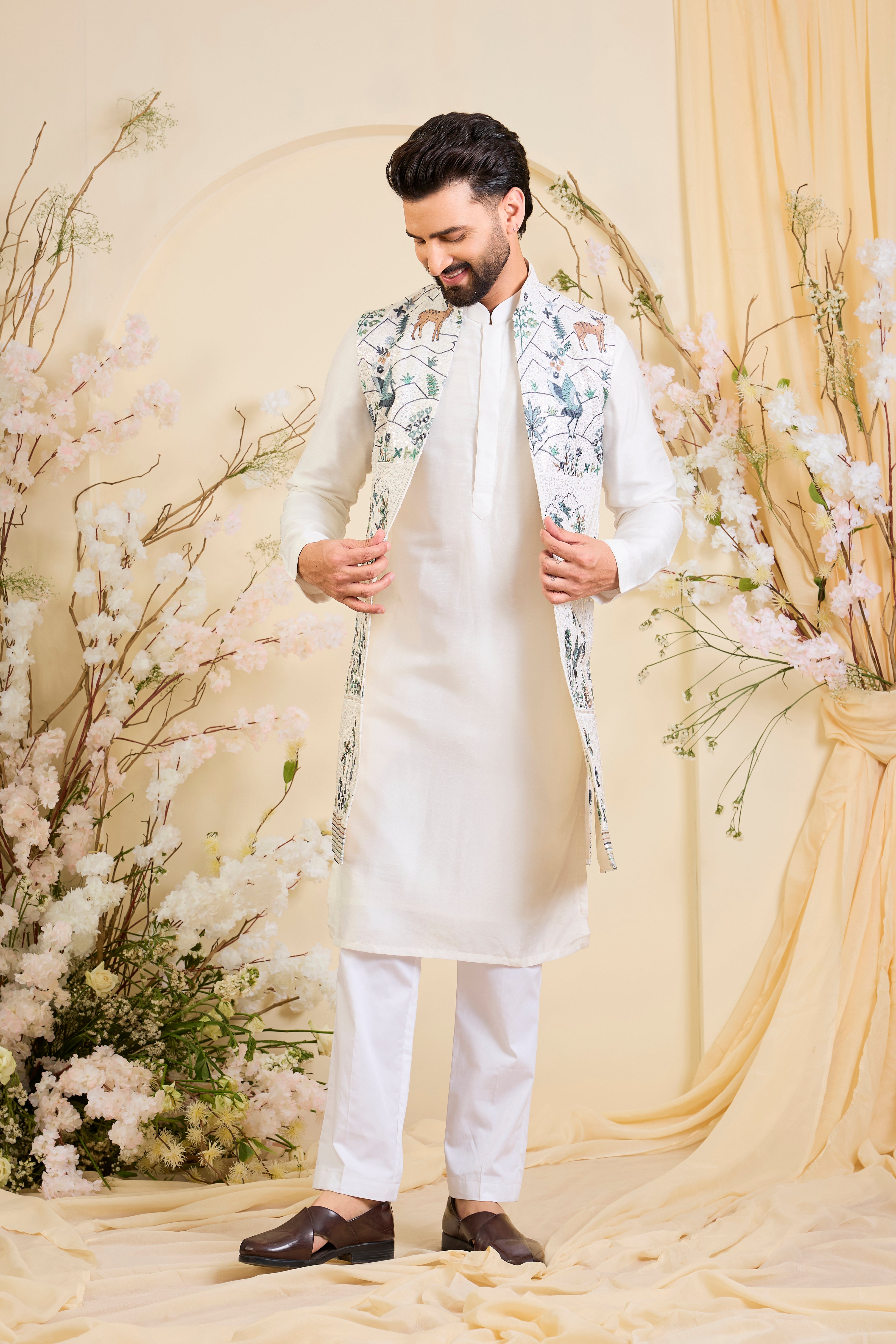 White long open jacket with intricate sequin work and detailed flora-fauna motifs, offering a luminous, richly layered couture statement.