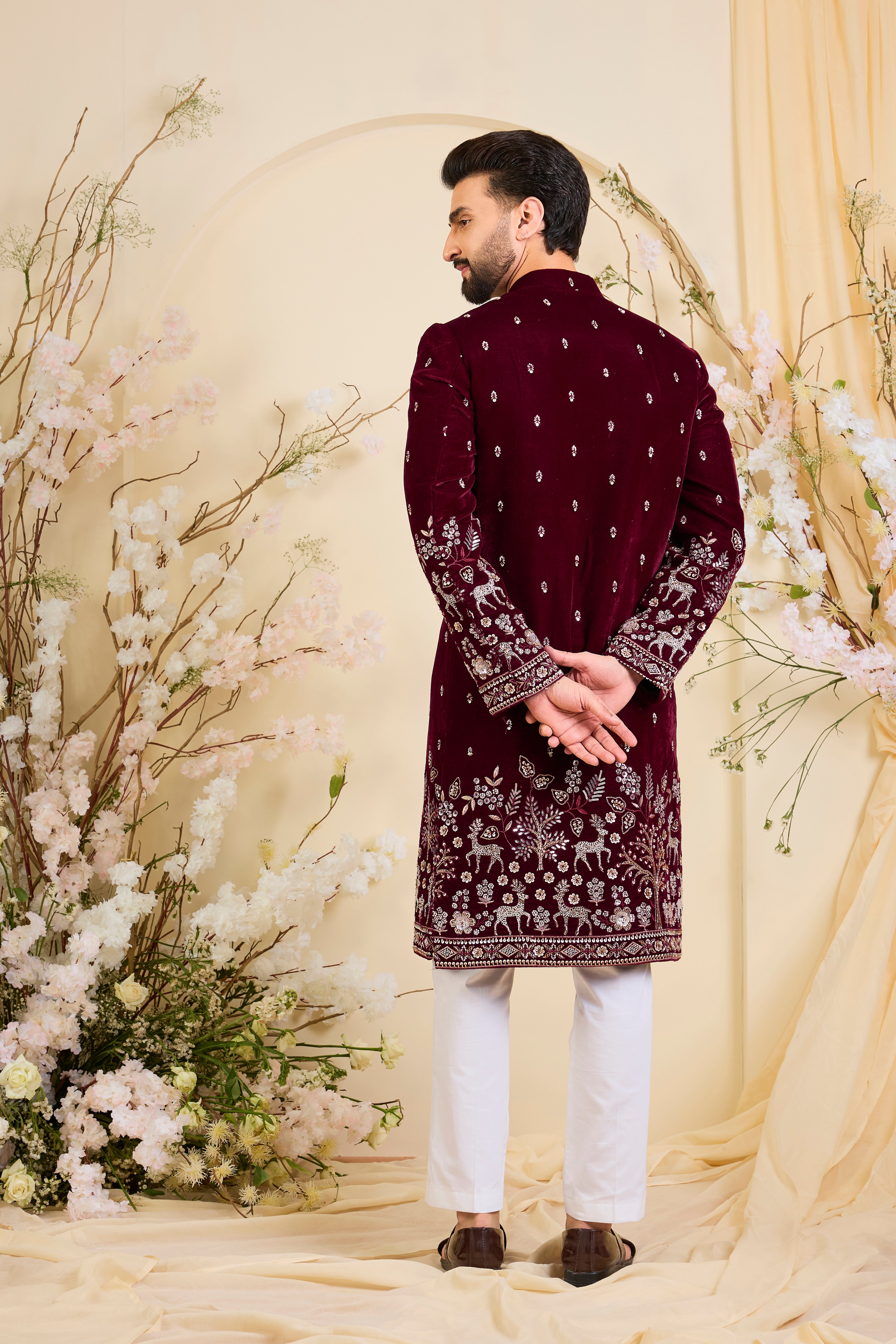An opulent maroon sherwani, intricately hand-embroidered with dense cut dana work and elaborate flora-fauna motifs, exuding regal depth and grand sophistication.