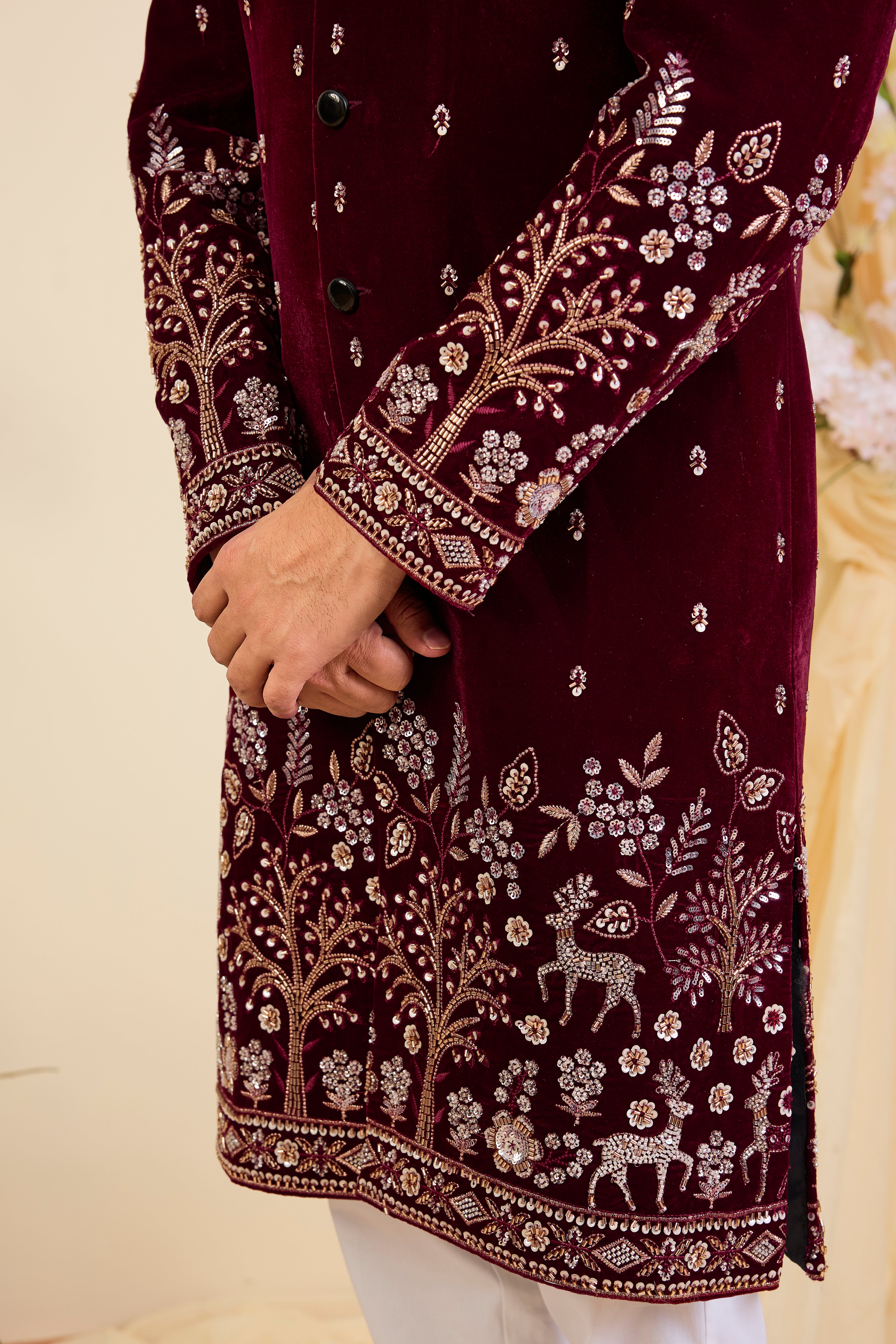 An opulent maroon sherwani, intricately hand-embroidered with dense cut dana work and elaborate flora-fauna motifs, exuding regal depth and grand sophistication.
