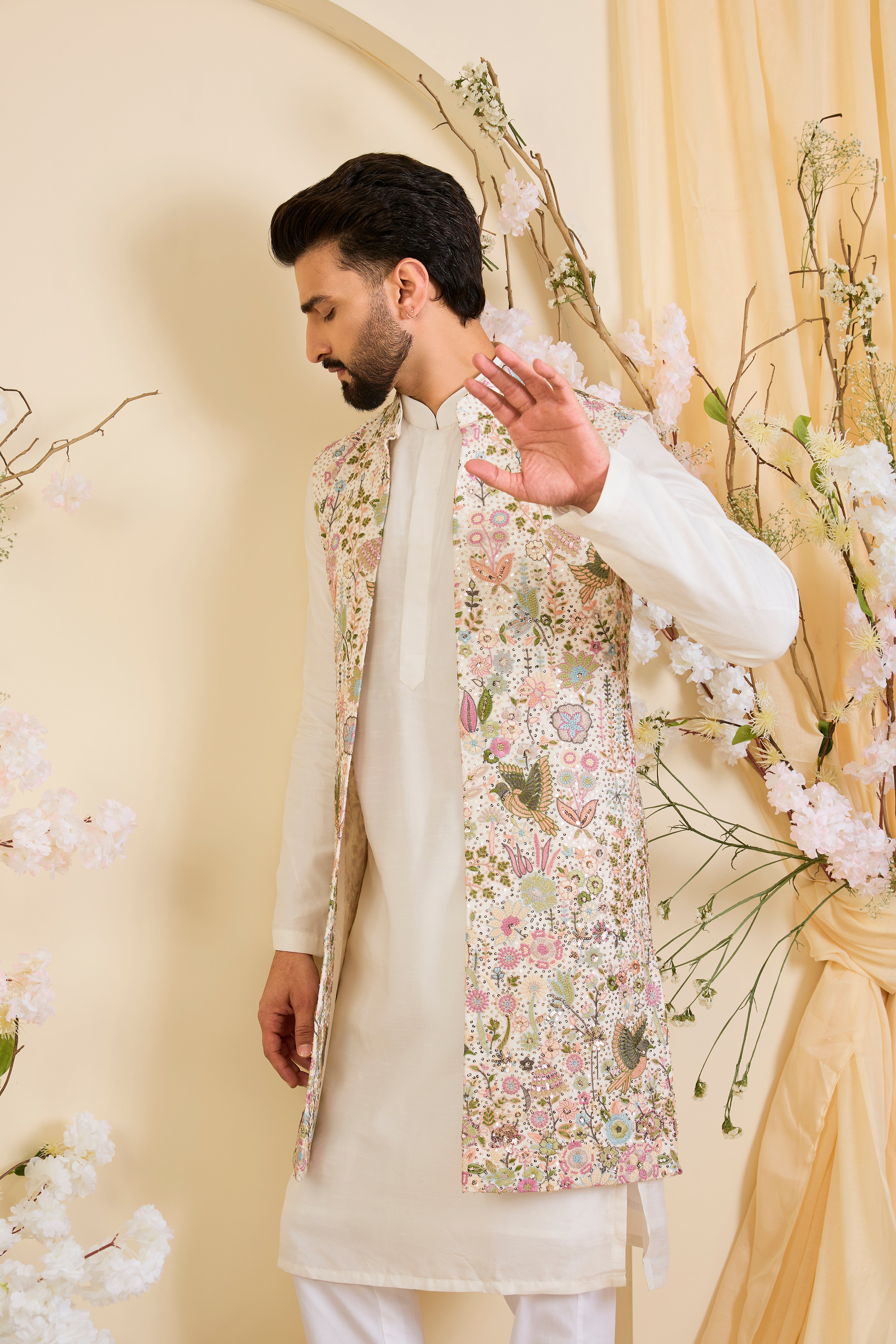 White long open jacket with intricate sequin work and detailed flora-fauna motifs, offering a luminous, richly layered couture statement.