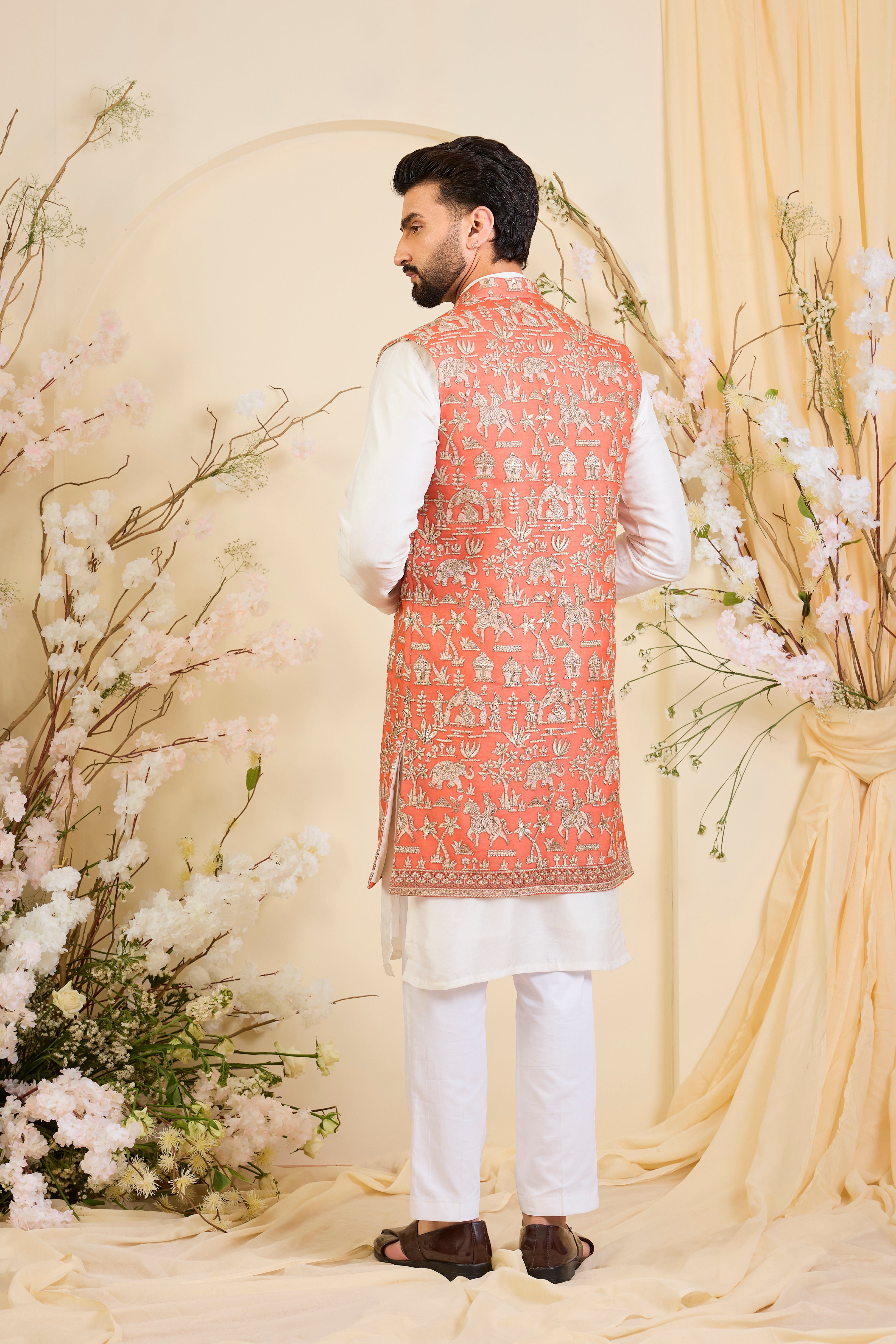 Orange long open jacket with intricate zari work, sequin detailing, and Mughal-era embroidery, delivering a richly layered, regal couture statement.