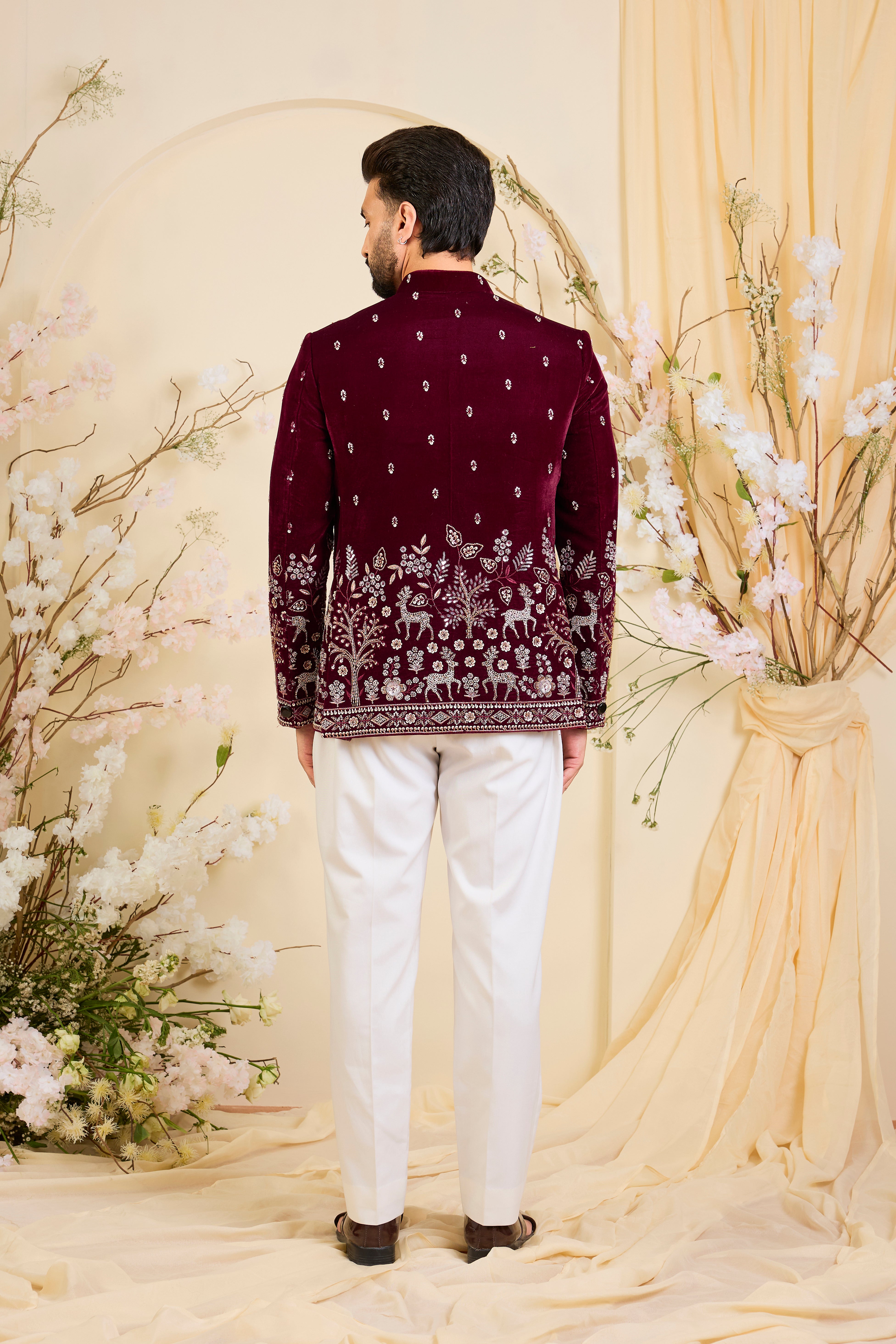 An opulent maroon bandgala , intricately hand-embroidered with dense cut dana work and elaborate flora-fauna motifs, exuding regal depth and grand sophistication.