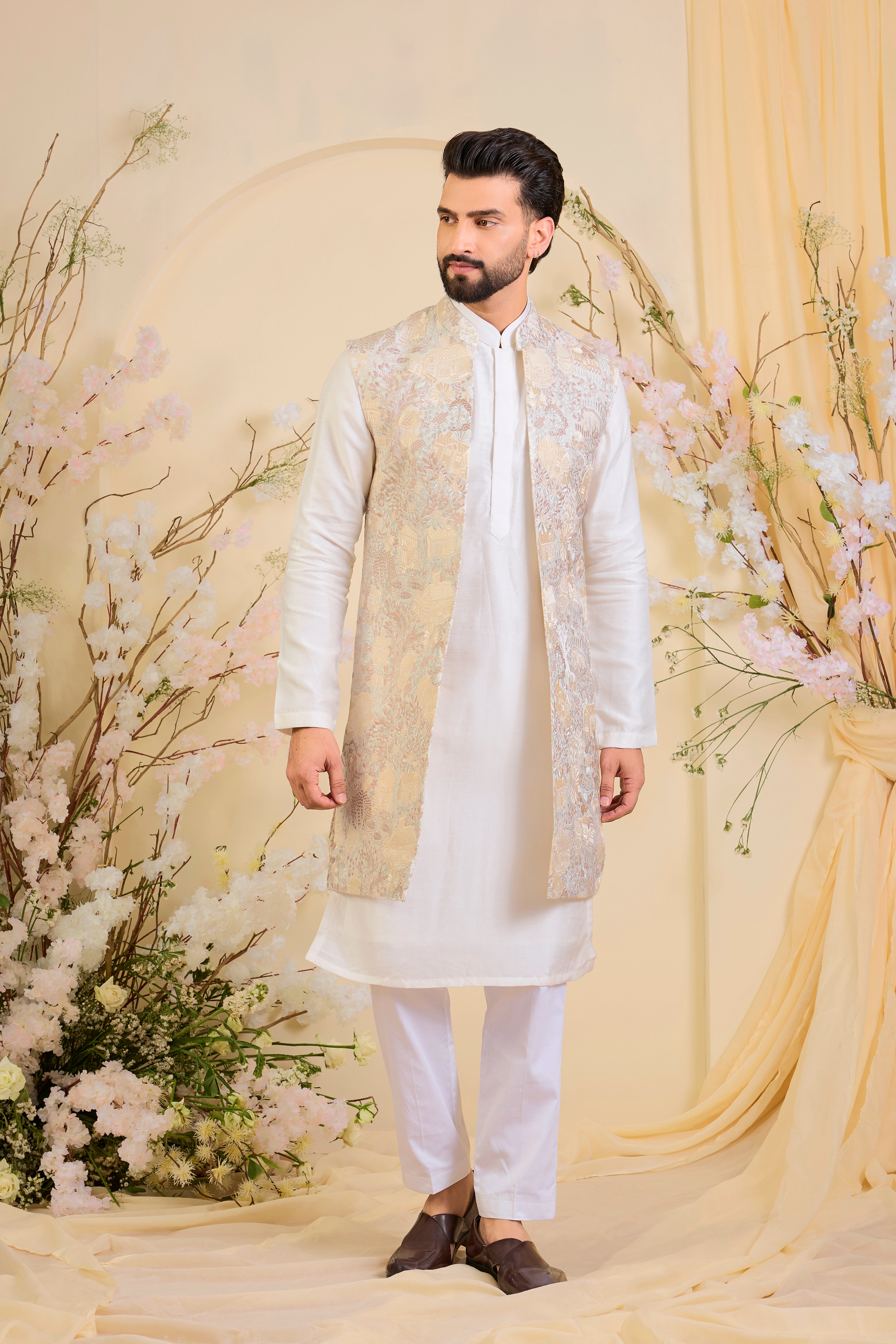 Beige-cream long open jacket with intricate flora-fauna embroidery and dense threadwork, offering a refined, richly textured couture statement.