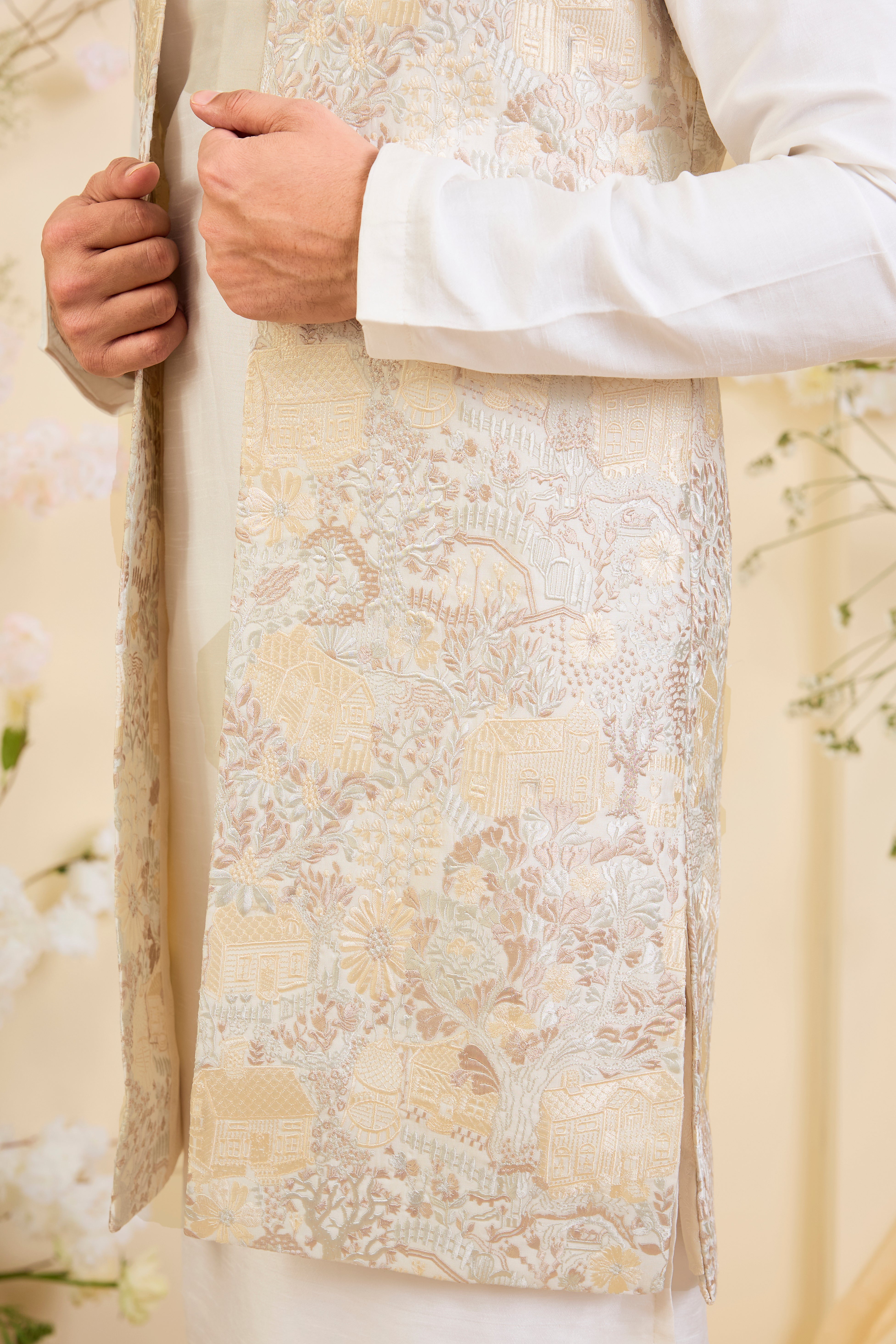 Beige-cream long open jacket with intricate flora-fauna embroidery and dense threadwork, offering a refined, richly textured couture statement.
