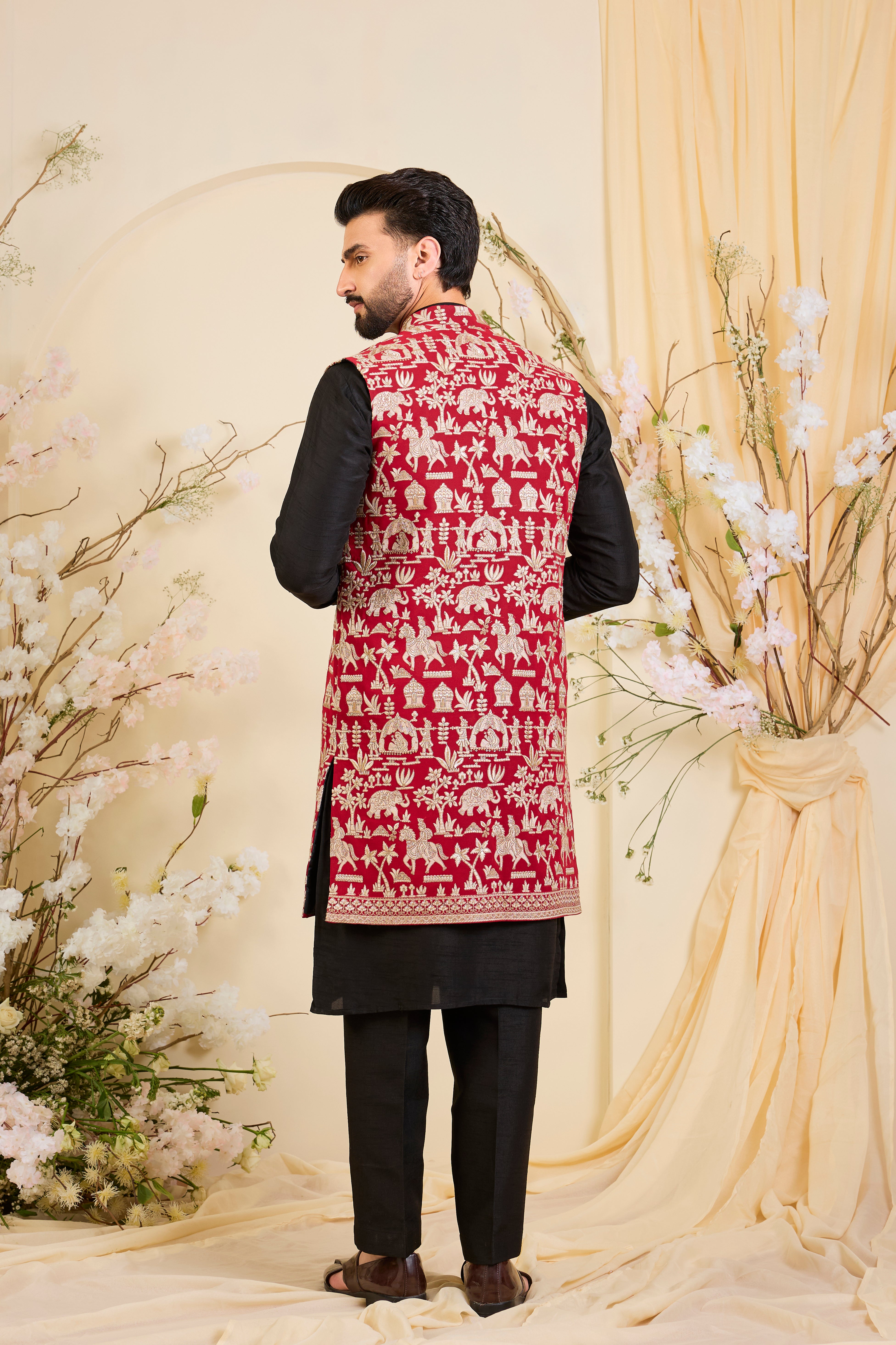 Red/pink long open jacket with intricate zari work, sequin detailing, and Mughal-era embroidery, delivering a richly layered, regal couture statement.