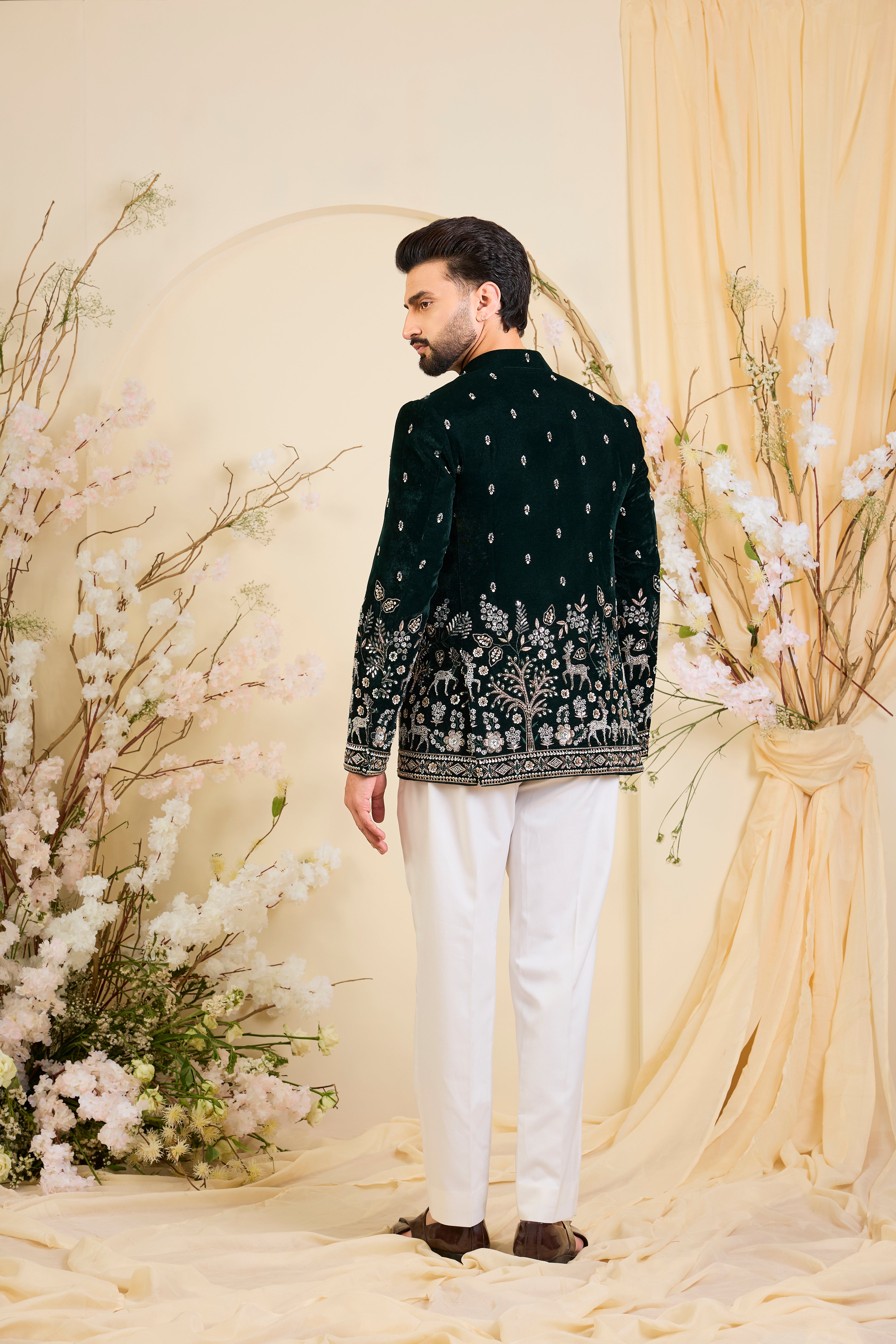 An opulent bottle green bandgala , intricately hand-embroidered with dense cut dana work and elaborate flora-fauna motifs, exuding regal depth and grand sophistication.