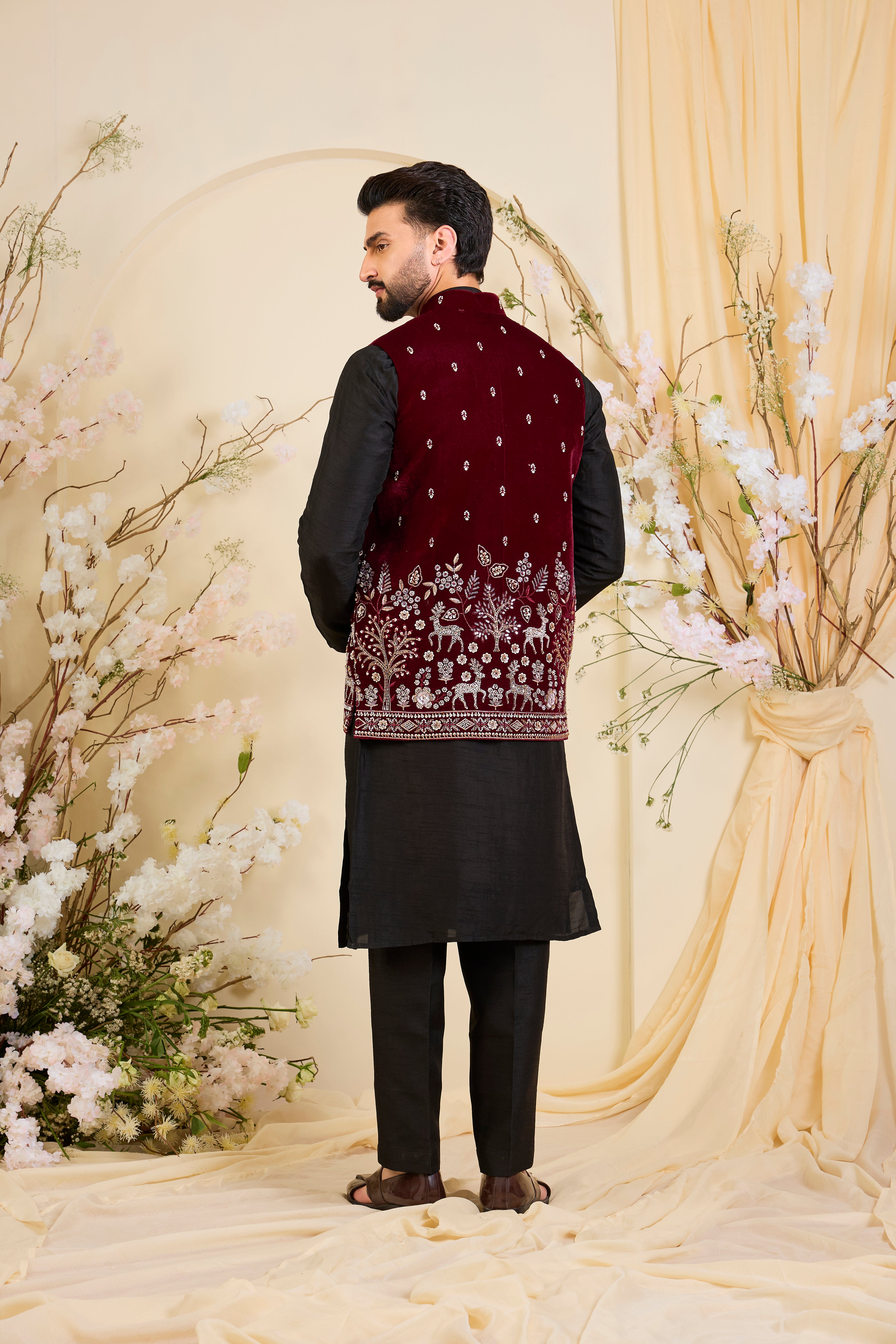 An opulent maroon nehru jacket , intricately hand-embroidered with dense cut dana work and elaborate flora-fauna motifs, exuding regal depth and grand sophistication.