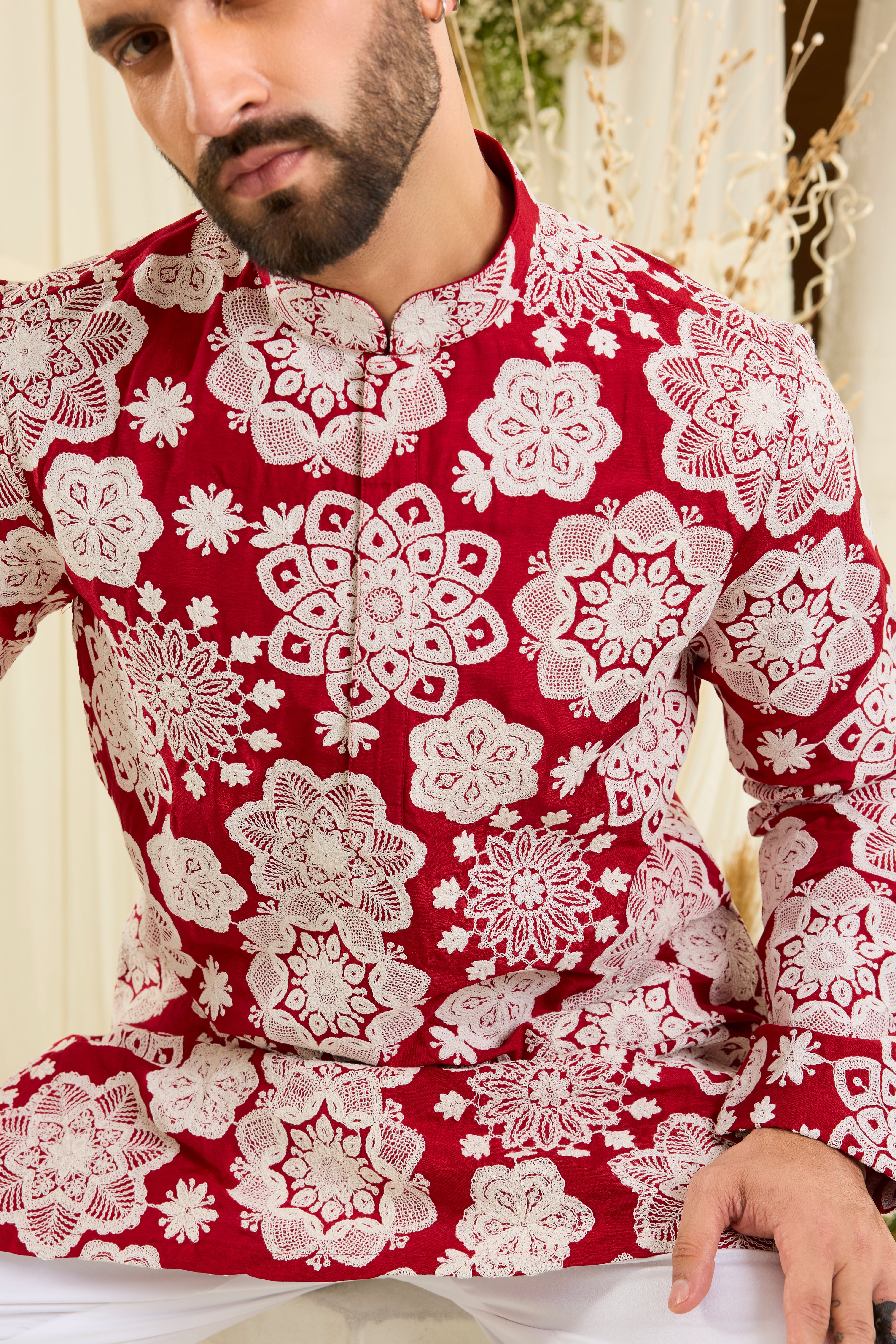 Red short kurta with intricate floral embroidery and heavy dori work, delivering a richly textured, bold festive statement.