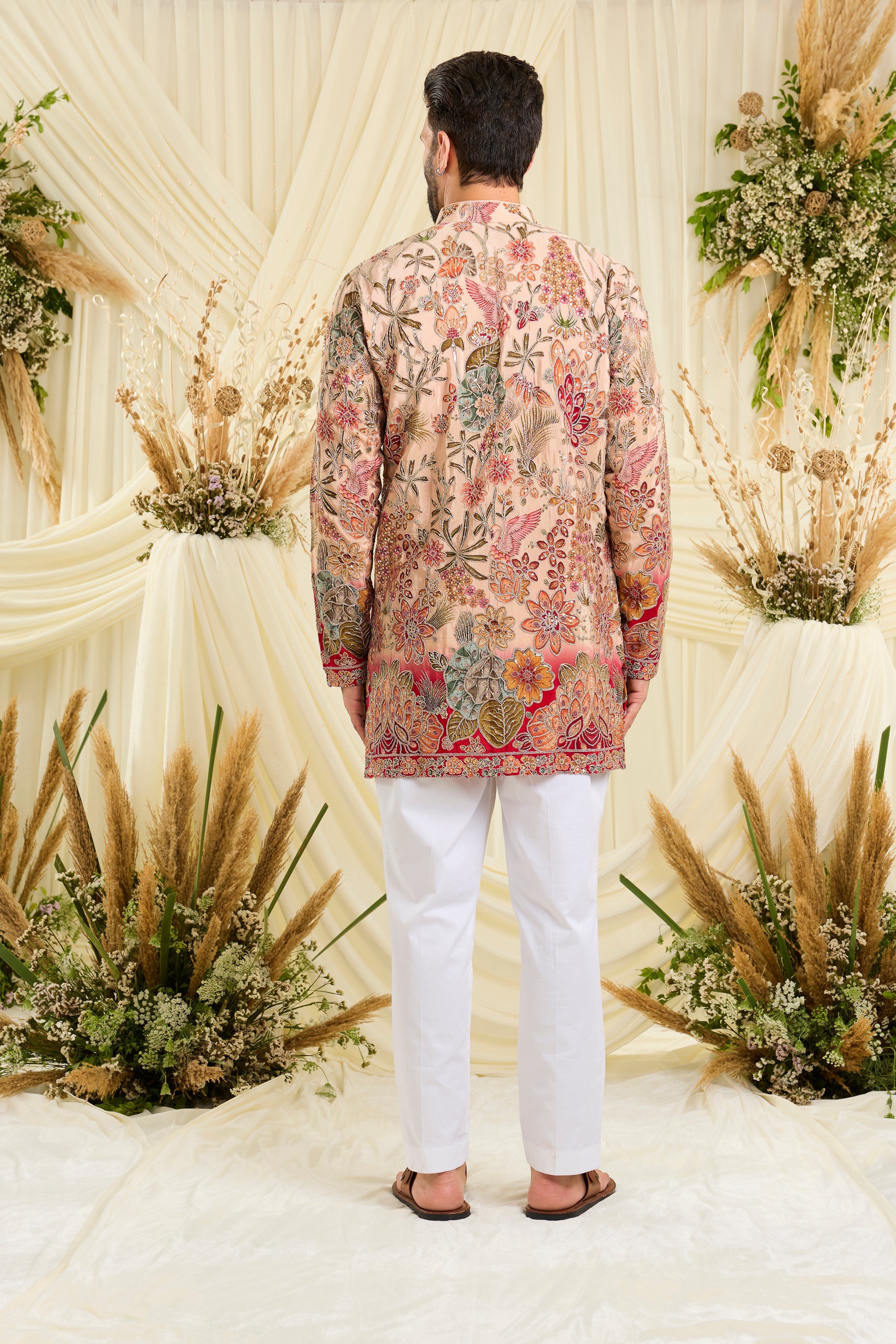 Pastel peach short kurta with intricate floral embroidery, rich zari detailing, and delicate sequins for a refined, luminous festive statement.