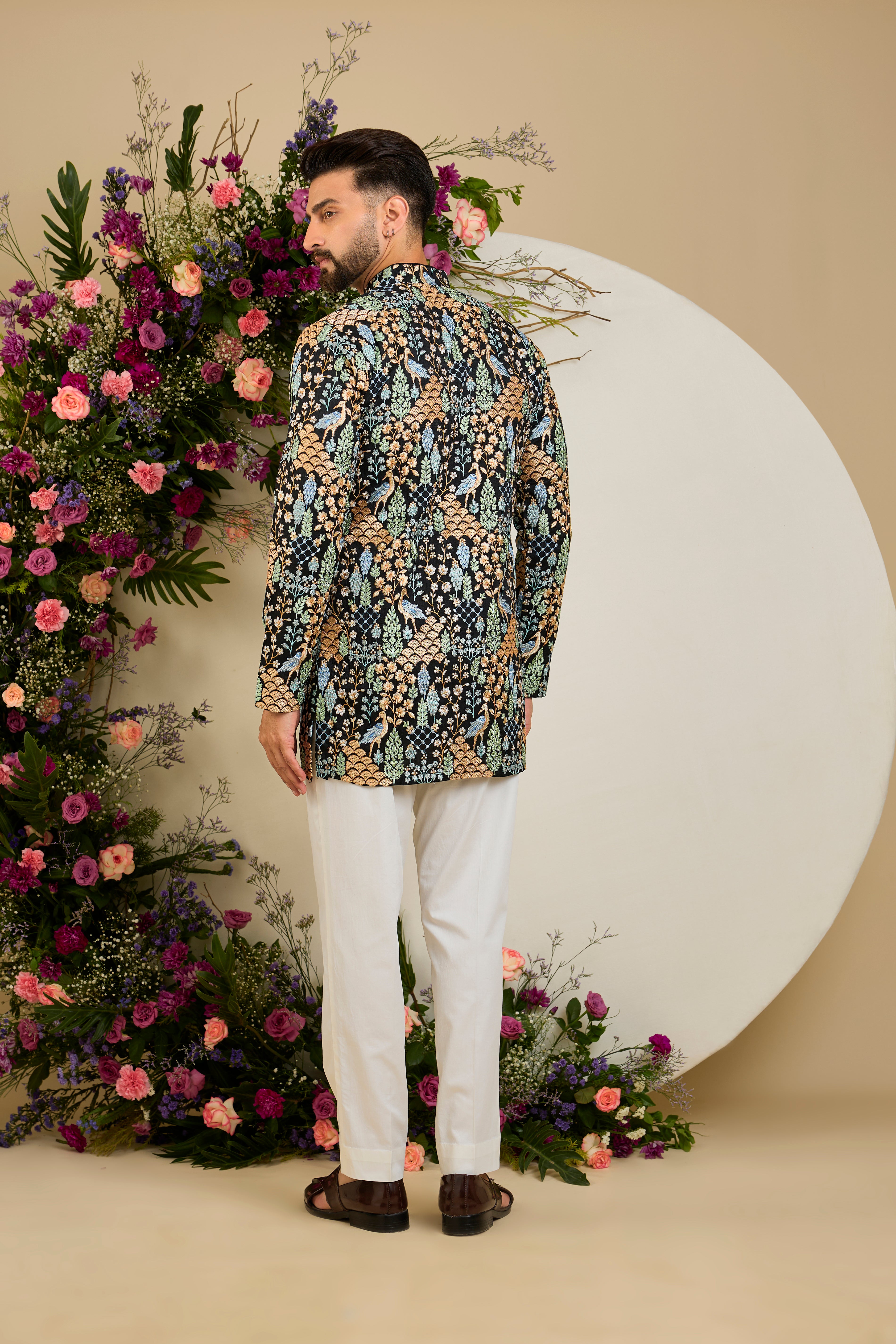 Black short kurta with tropical flora and fauna embroidery, vibrant threadwork, and delicate sequins for refined formal elegance.
