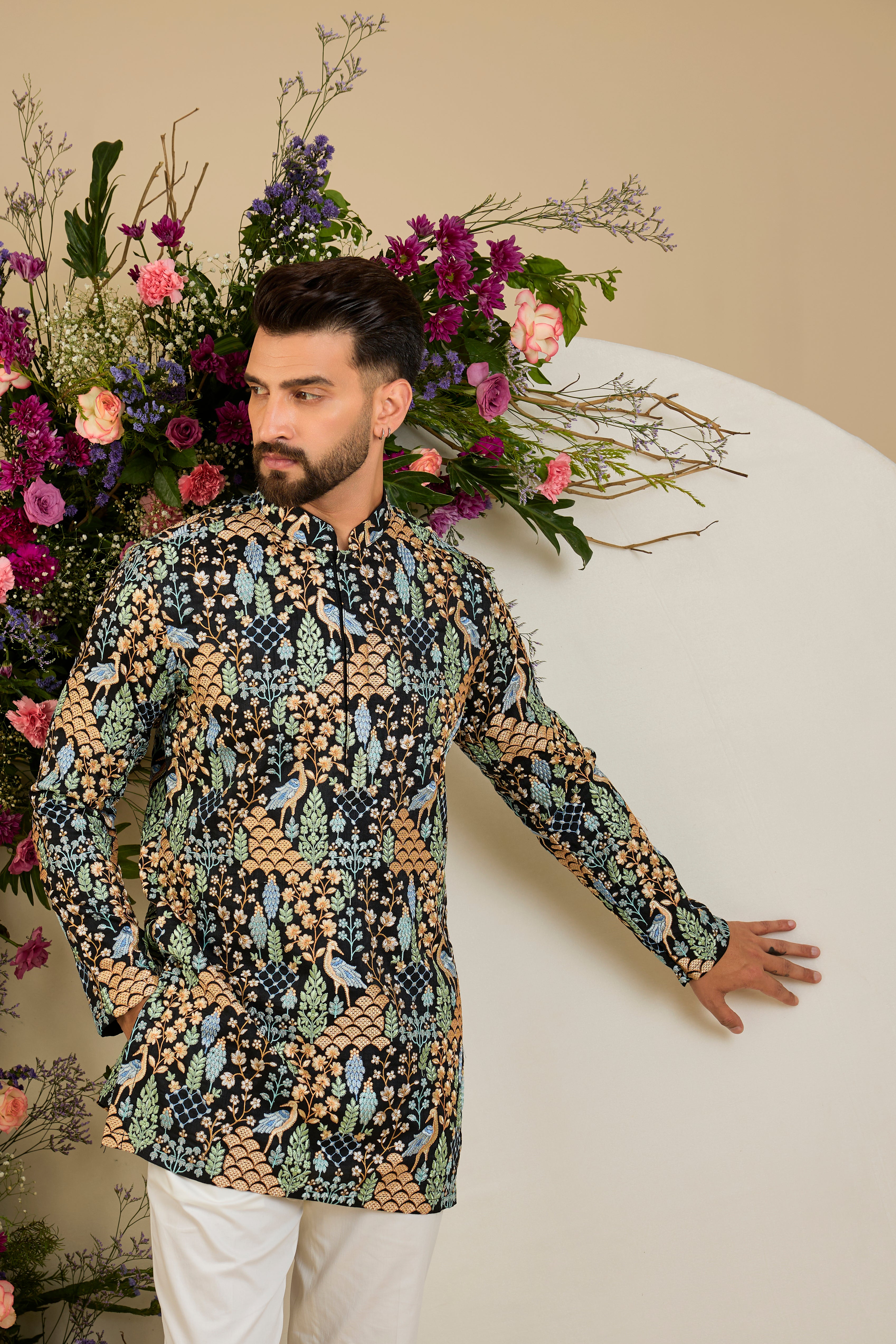 Black short kurta with tropical flora and fauna embroidery, vibrant threadwork, and delicate sequins for refined formal elegance.