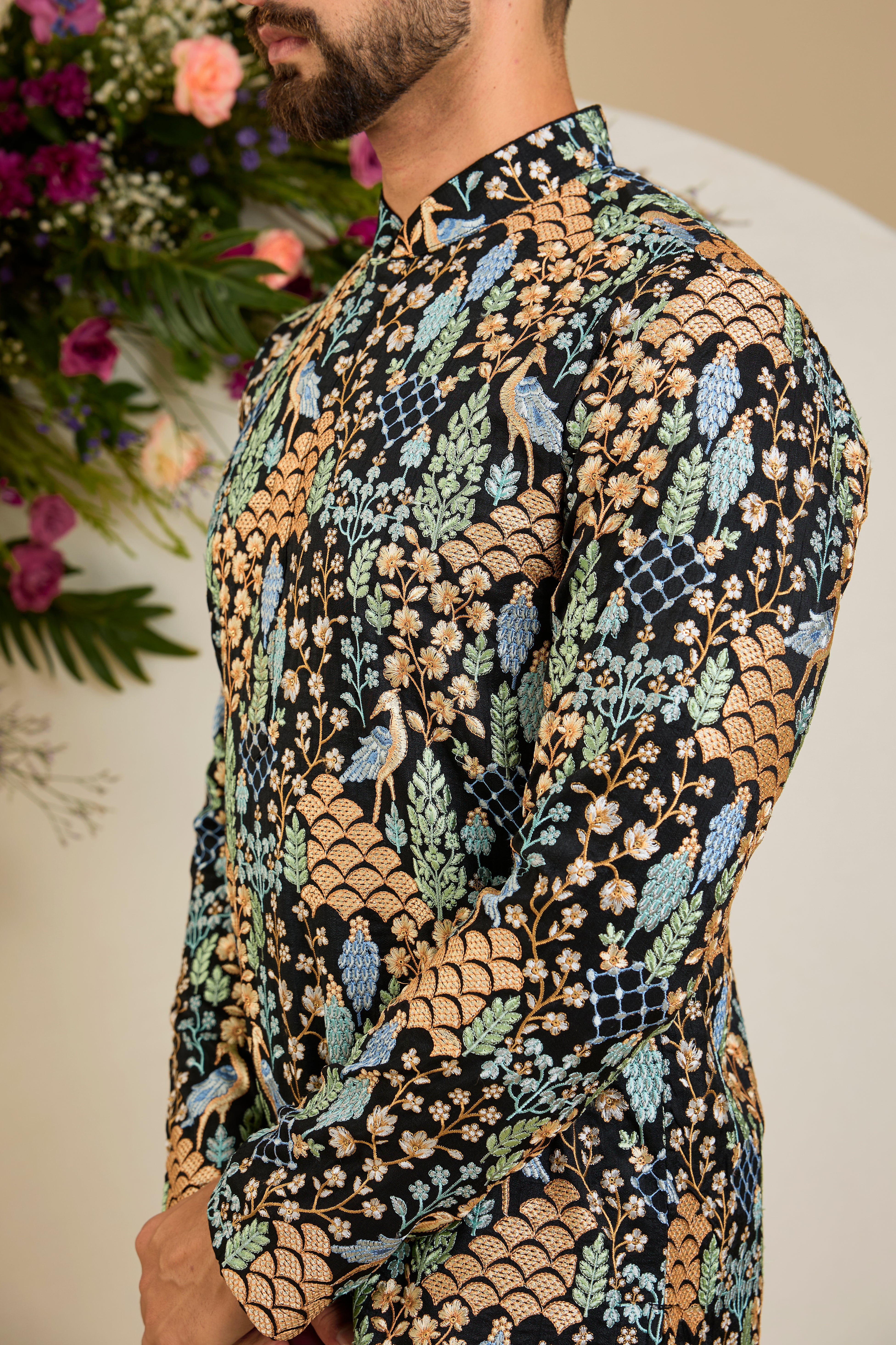 Black short kurta with tropical flora and fauna embroidery, vibrant threadwork, and delicate sequins for refined formal elegance.
