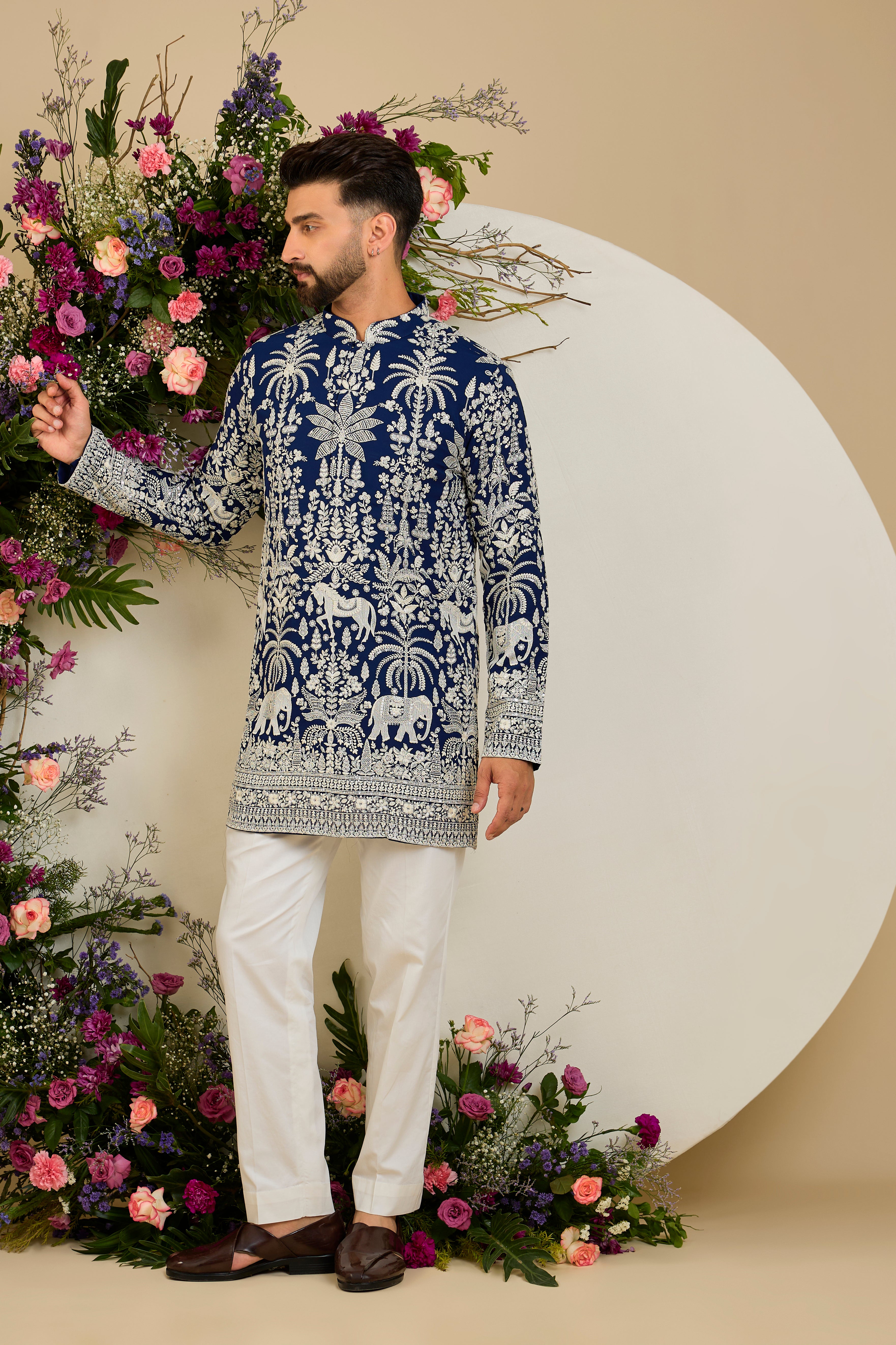 Royal blue short kurta with tropical flora and fauna embroidery, ivory threadwork, and delicate sequin detailing for refined occasion wear.