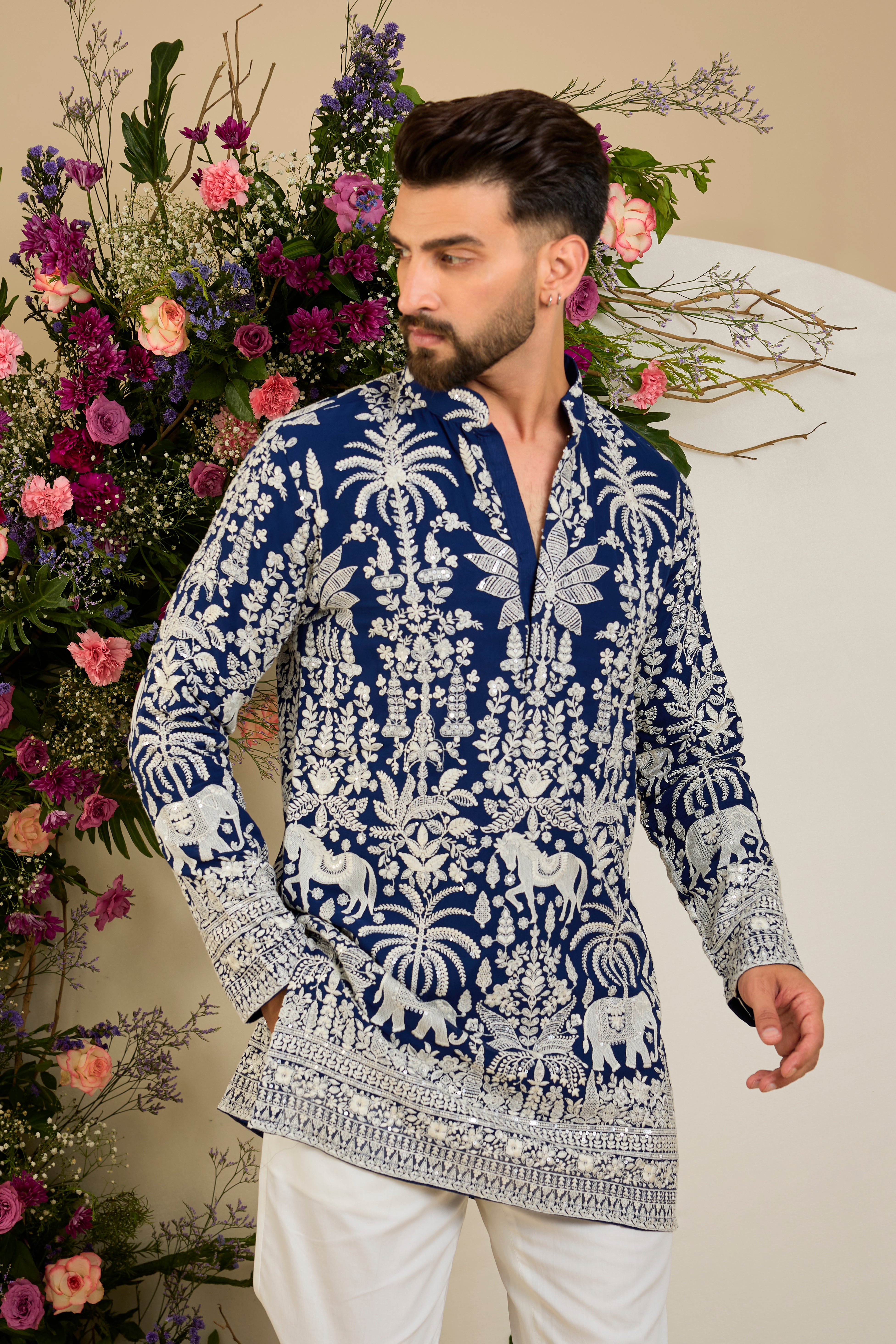 Royal blue short kurta with tropical flora and fauna embroidery, ivory threadwork, and delicate sequin detailing for refined occasion wear.
