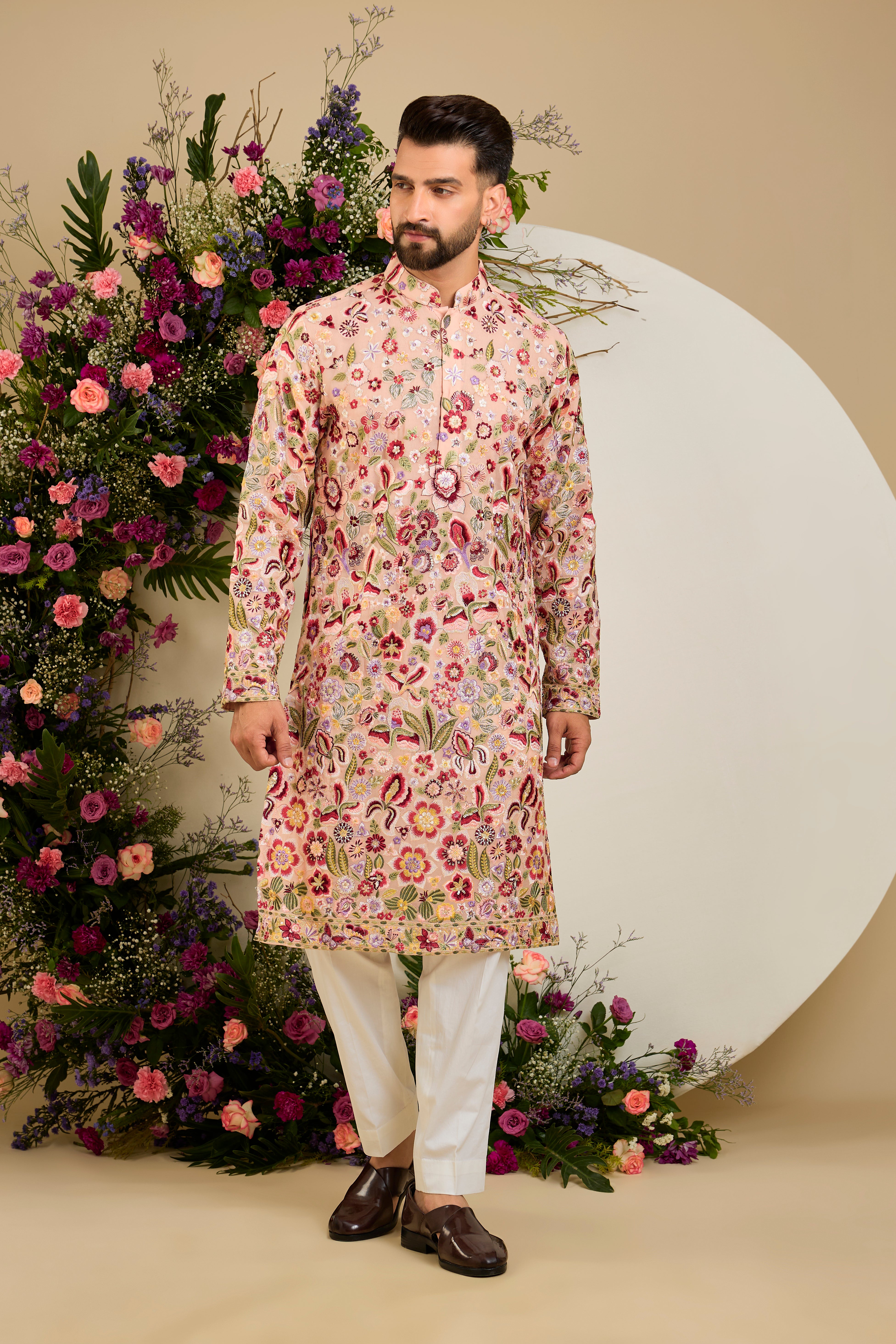 Blush peach pastel kurta with a vibrant floral backdrop, multi-coloured thread embroidery, and delicate sequin detailing for timeless elegance.