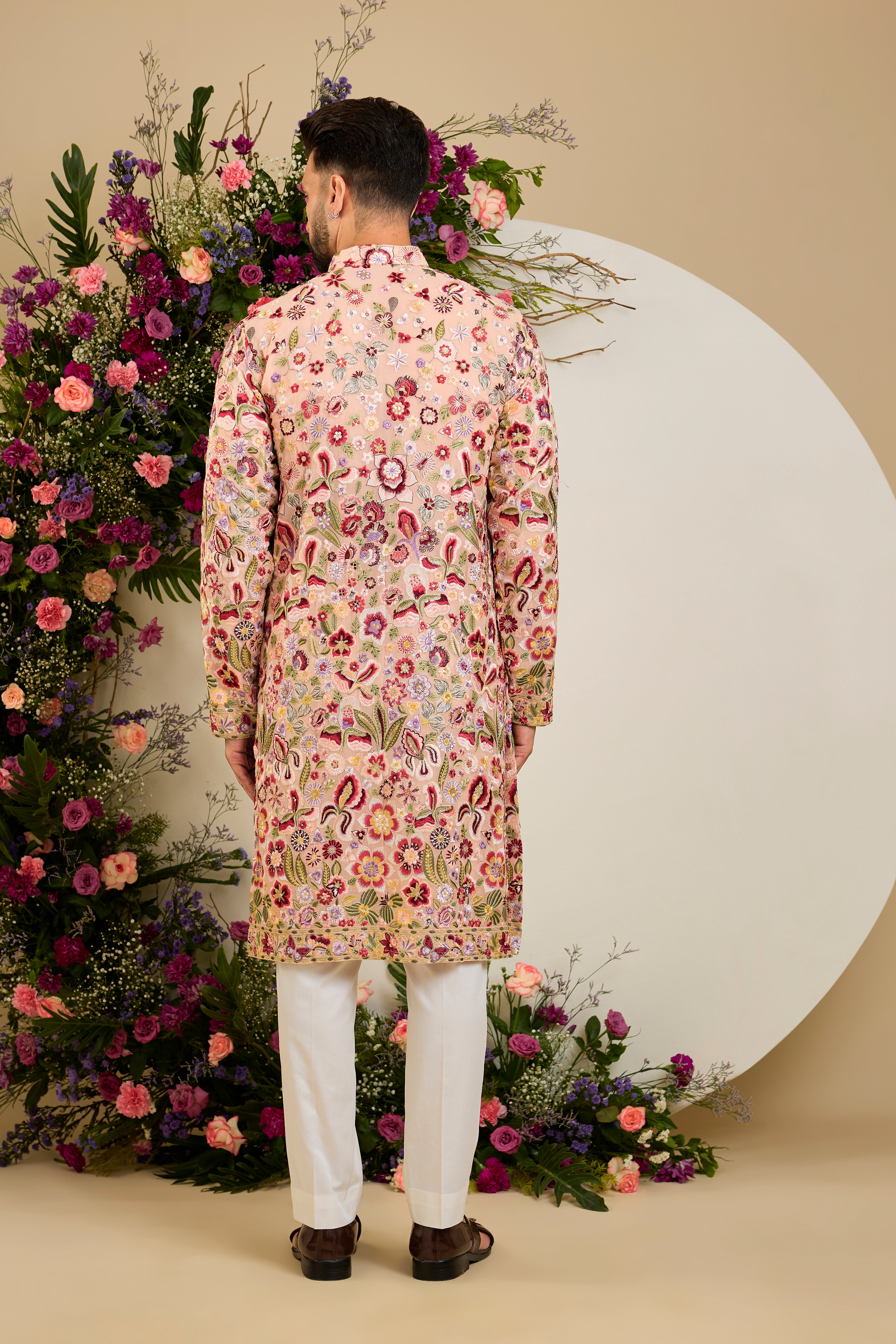 Blush peach pastel kurta with a vibrant floral backdrop, multi-coloured thread embroidery, and delicate sequin detailing for timeless elegance.