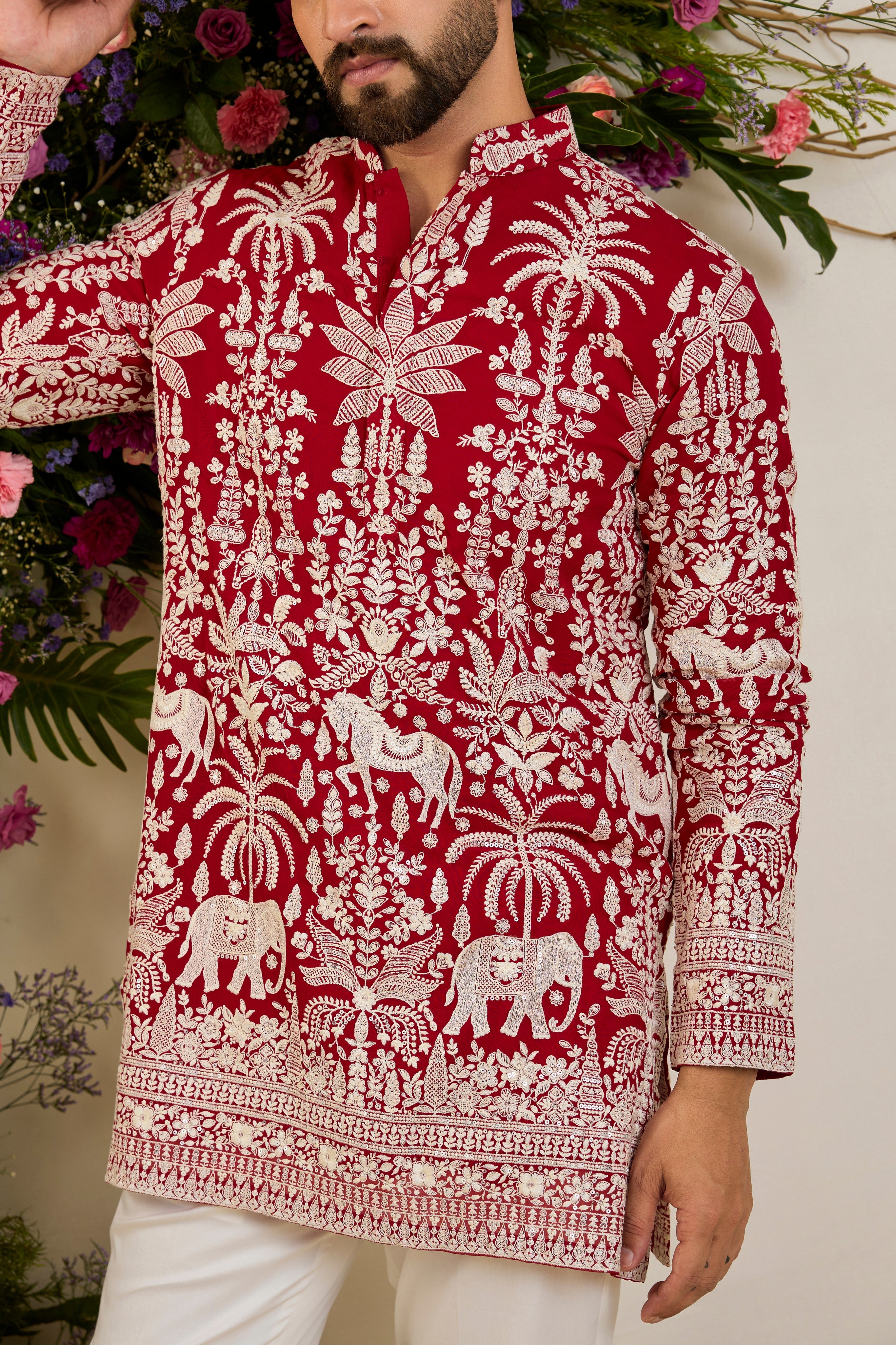 Red short kurta with tropical flora and fauna embroidery, ivory threadwork, and delicate sequin detailing for refined occasion wear.