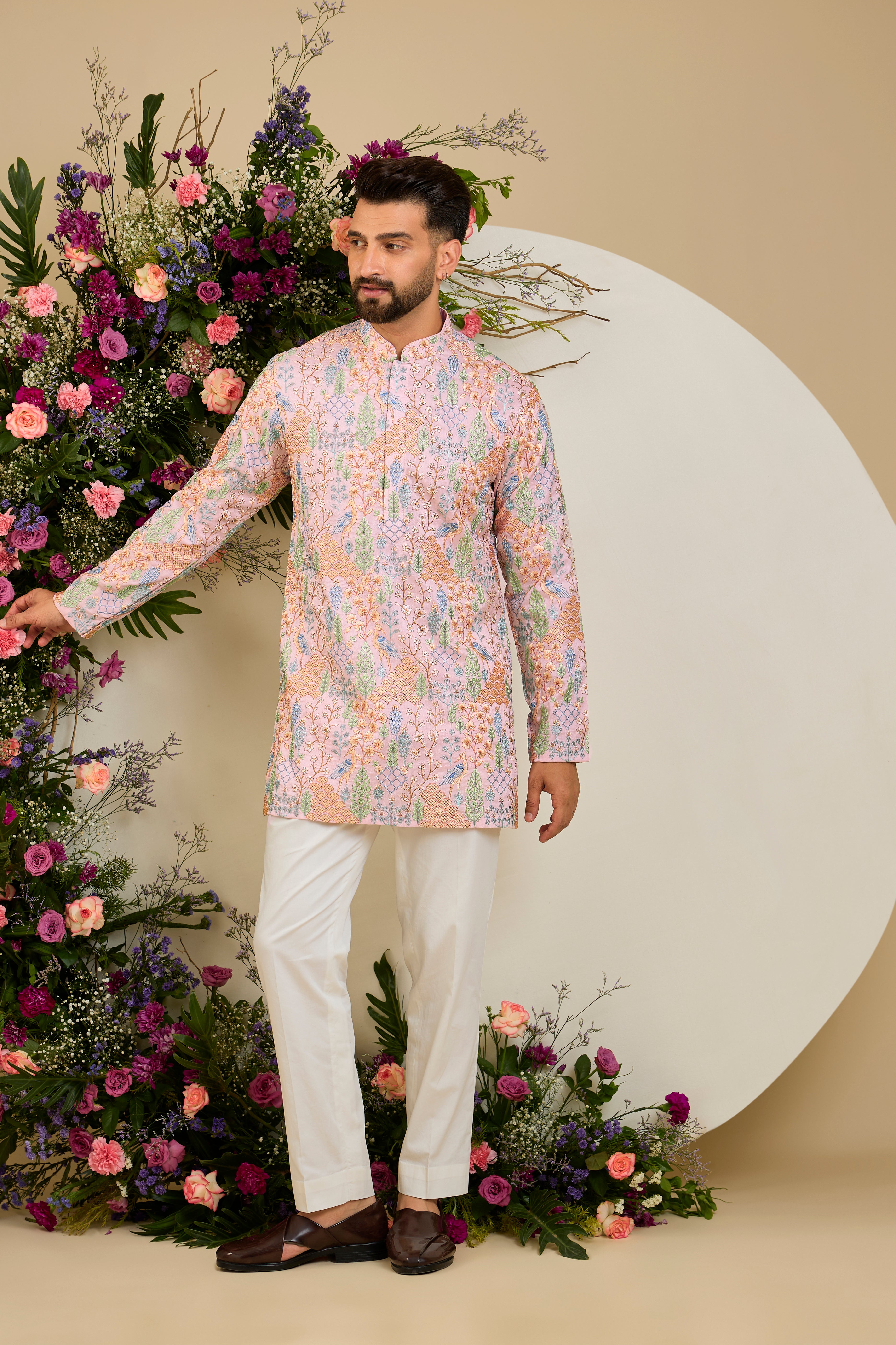 Blush pink short kurta with tropical flora and fauna embroidery, vibrant threadwork, and delicate sequins for refined formal elegance.