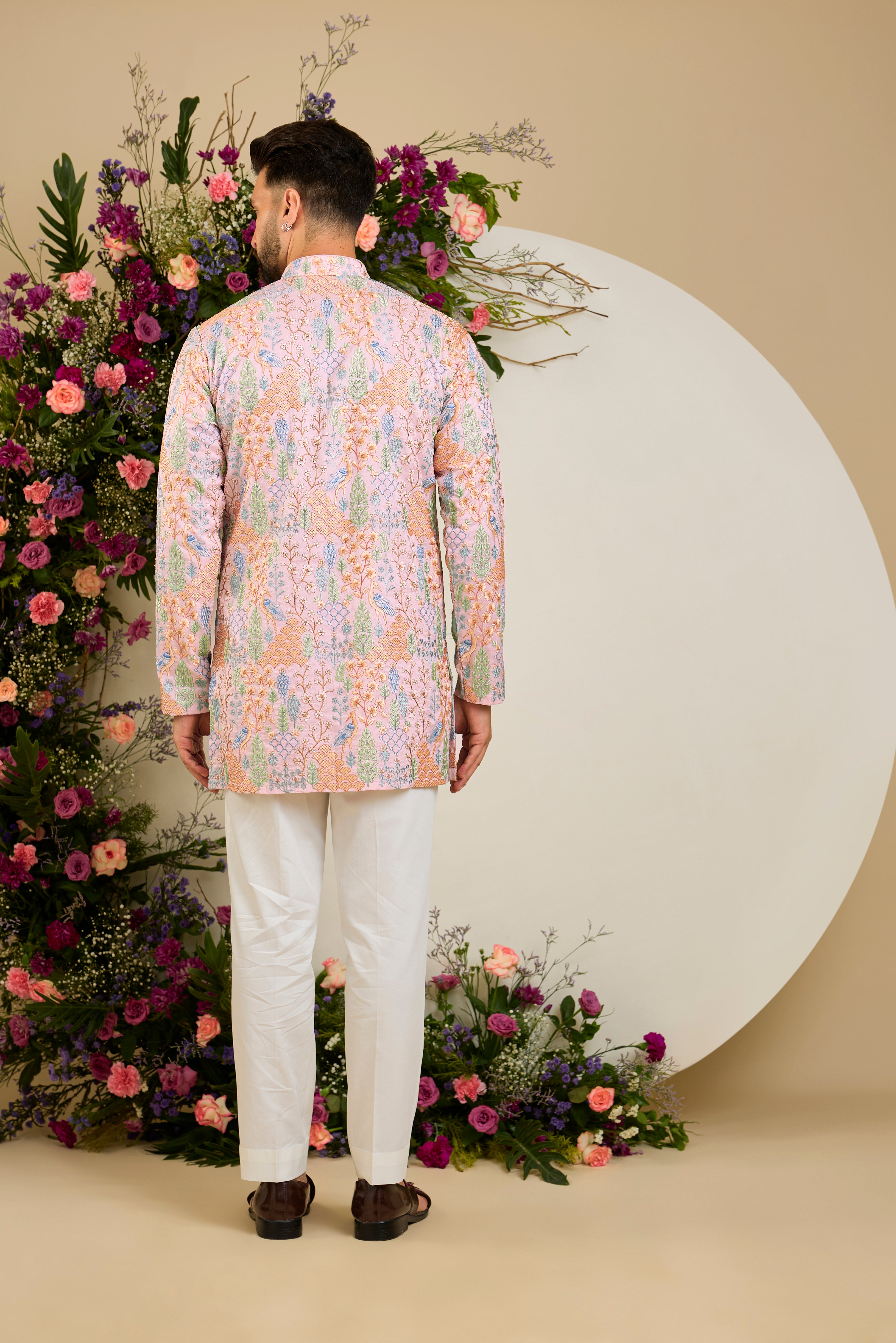 Blush pink short kurta with tropical flora and fauna embroidery, vibrant threadwork, and delicate sequins for refined formal elegance.