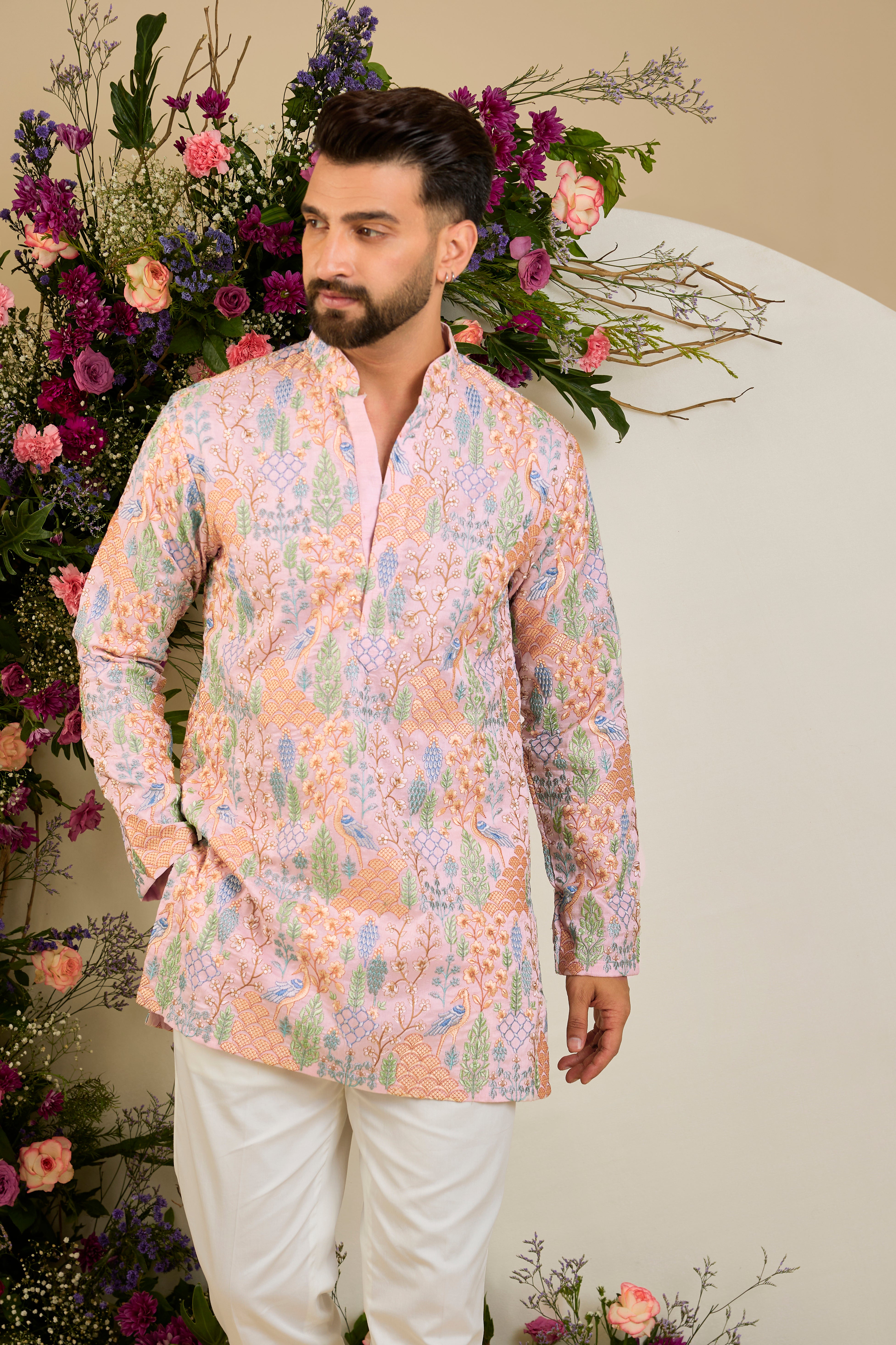 Blush pink short kurta with tropical flora and fauna embroidery, vibrant threadwork, and delicate sequins for refined formal elegance.