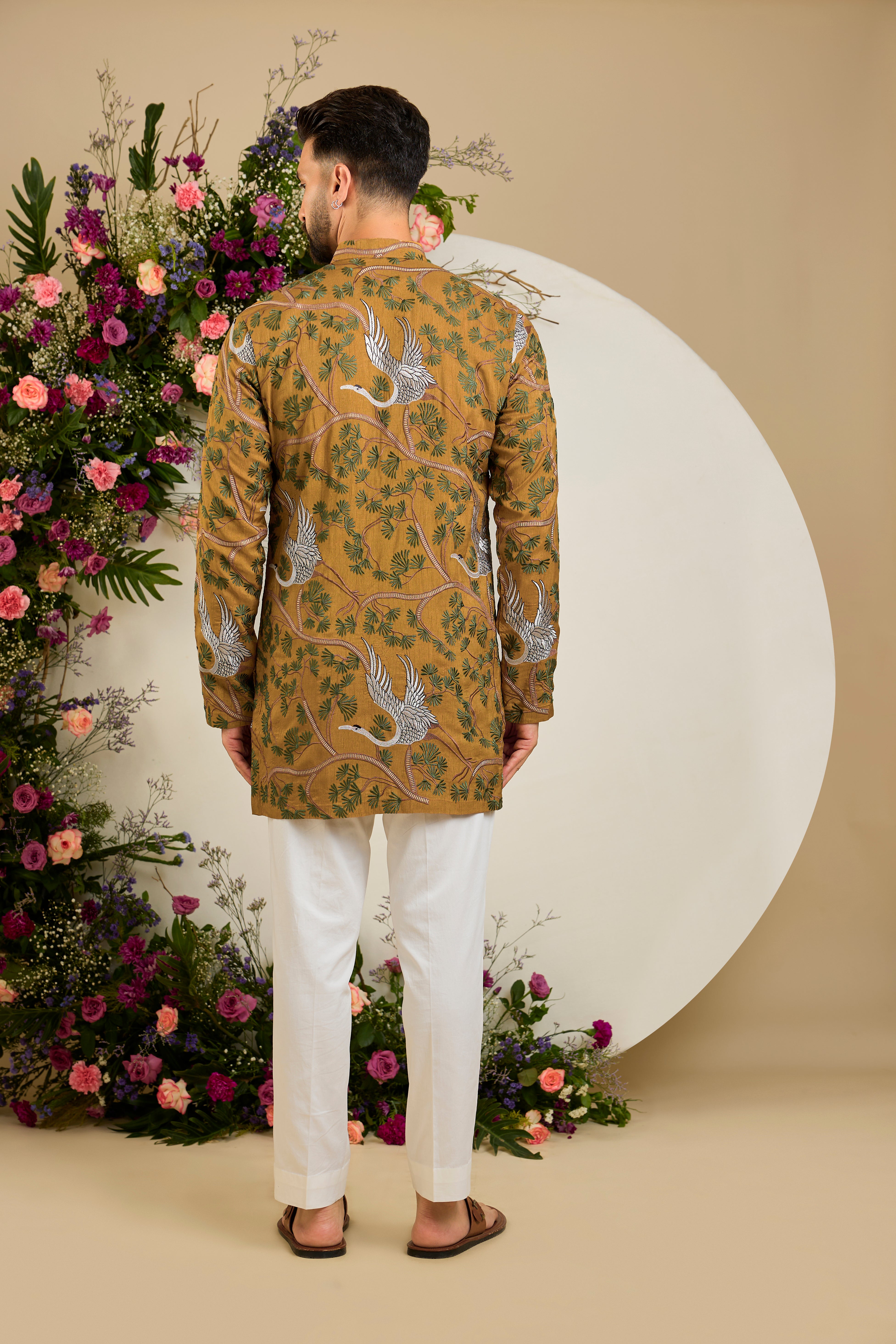 Mustard short kurta with a tropical backdrop, graceful flamingo motifs, intricate threadwork, and delicate sequin embellishments.