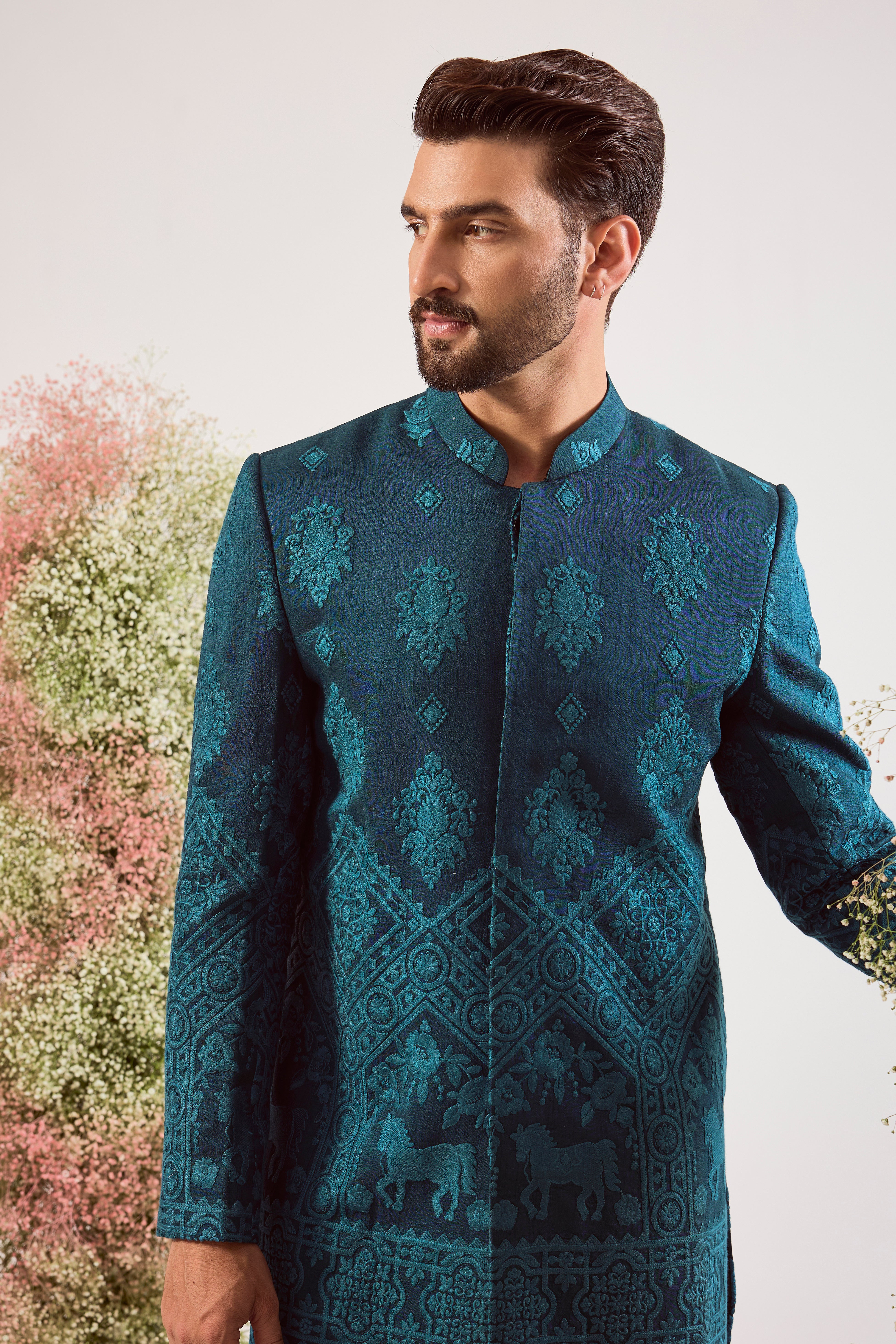 This stunning teal thread work short sherwani is a masterpiece of modern artistry. The rich, deep hue provides a luxurious canvas for the intricate threadwork, while the beautifully hand-stitched horse figures add a powerful and distinctive touch.