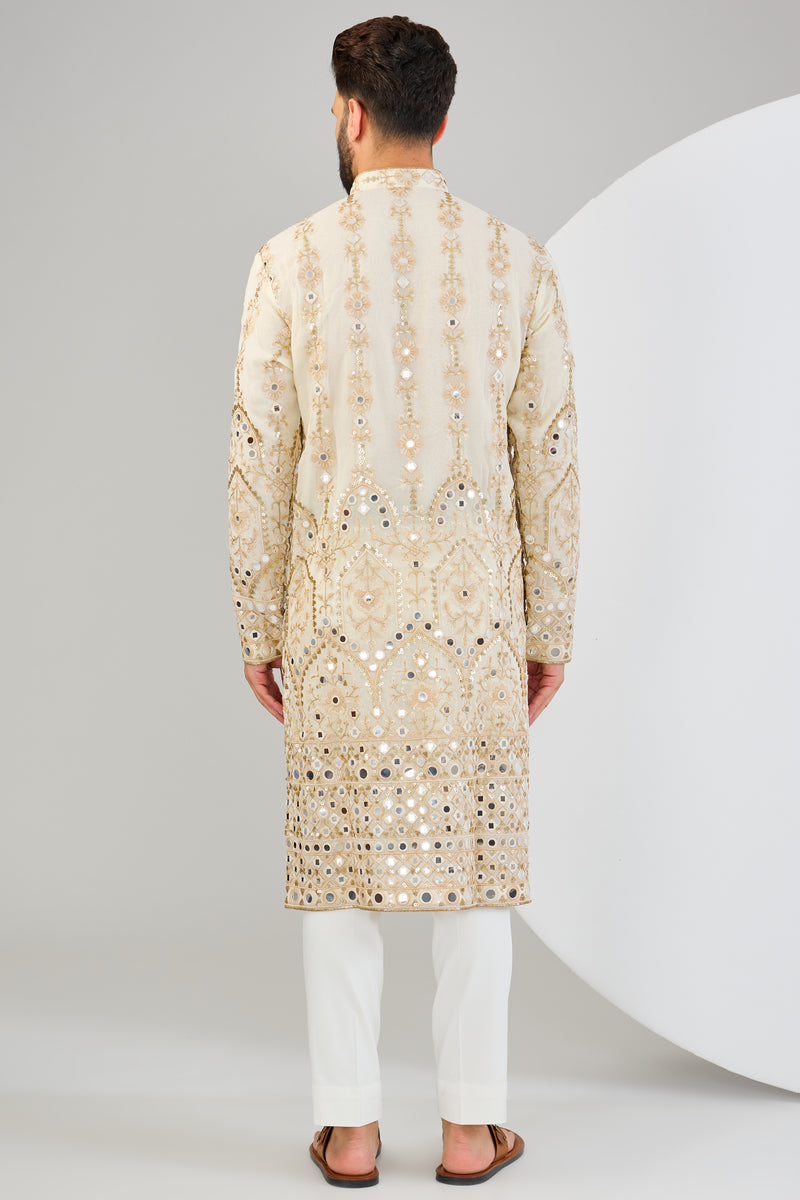 Cream mirror work kurta with detailed neckline and ghera with gold zari highlighting.