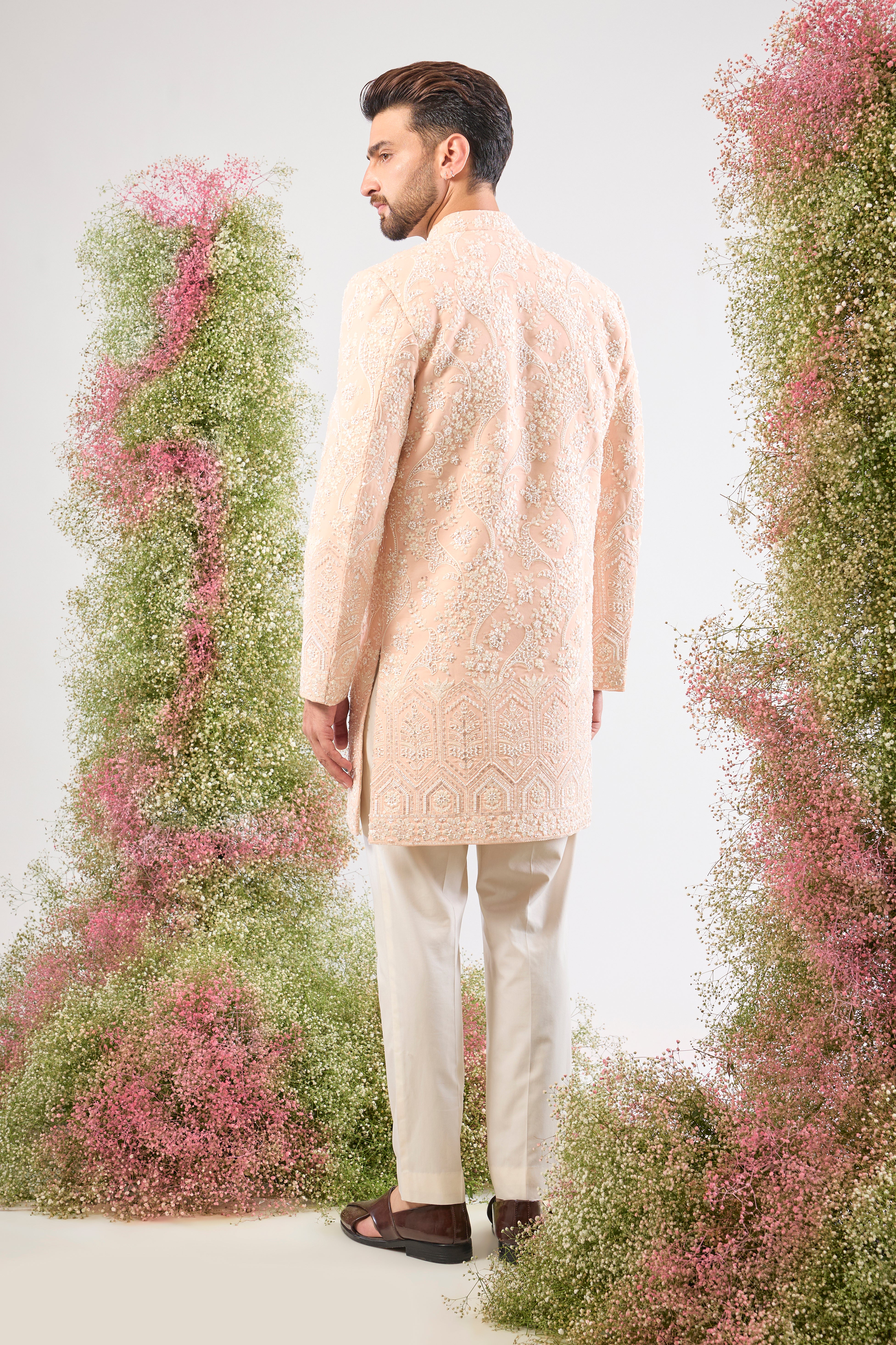 Artistry in attire! Our Pink Short Sherwani is adorned with a charming Floral Pattern brought to life using precise Hand Embroidered Cut Dana and shimmering, Delicate Sequins. The result is a sherwani that is both vibrant and exquisitely detailed. 🎨