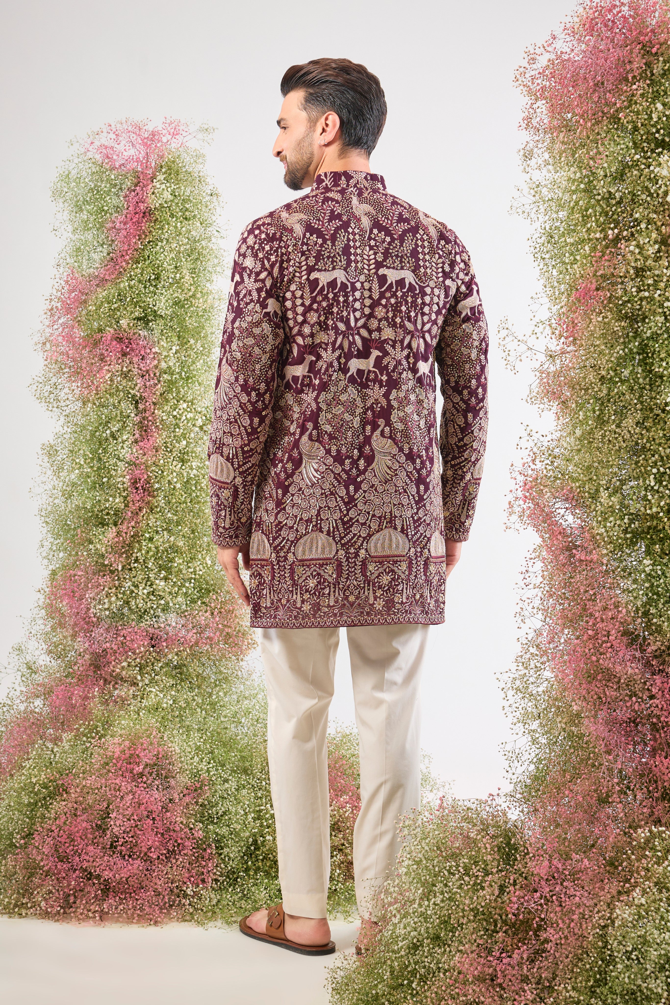 This Wine Short Kurta showcases stunning artistry, where Detailed Royal Darbars meet lush Flora and Fauna Figures. The entire design is beautifully textured and illuminated by rich Zari and Sequins.
