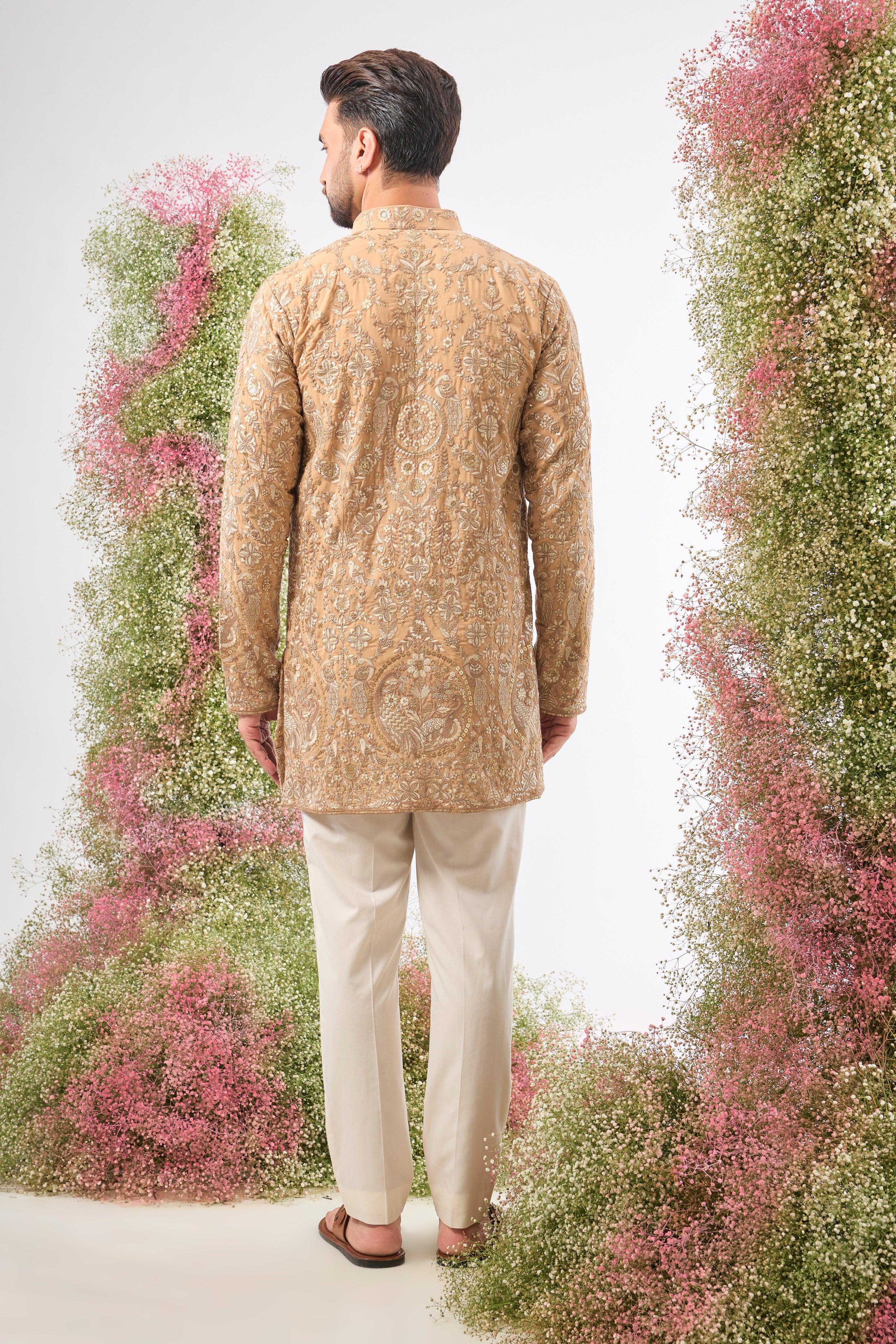 This Nude Short Kurta showcases magnificent Detailed Flora and Fauna Figures, creating depth and texture on the fabric. The combination of fine Zari and Sequin Work offers a delicate yet compelling shimmer.