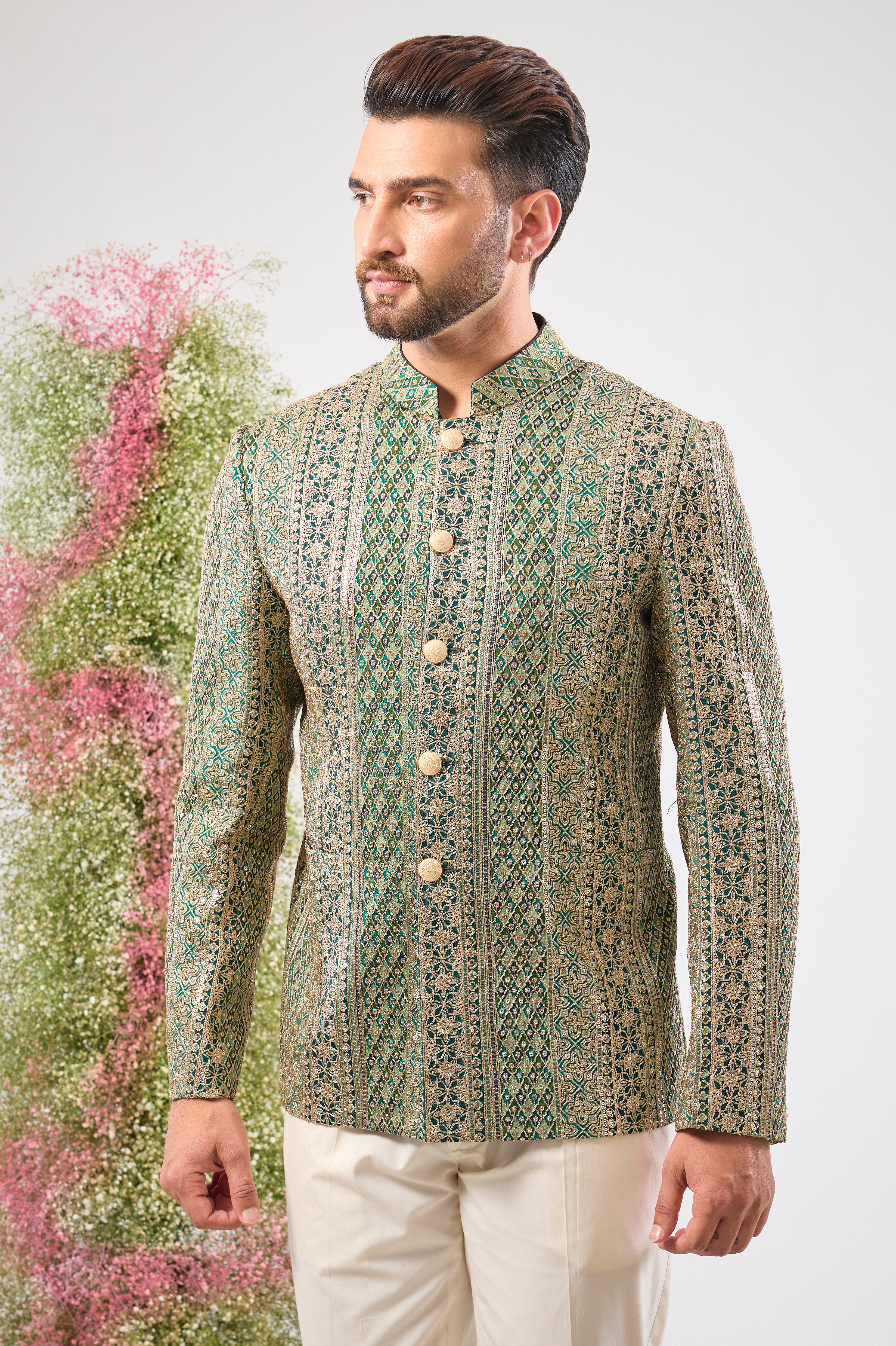 This Bottle Green Bandhgala is lavishly covered in Heavy Zari Work and sequin accents. The inclusion of Classy Metal Buttons ensures every detail of this garment speaks of high sophistication.