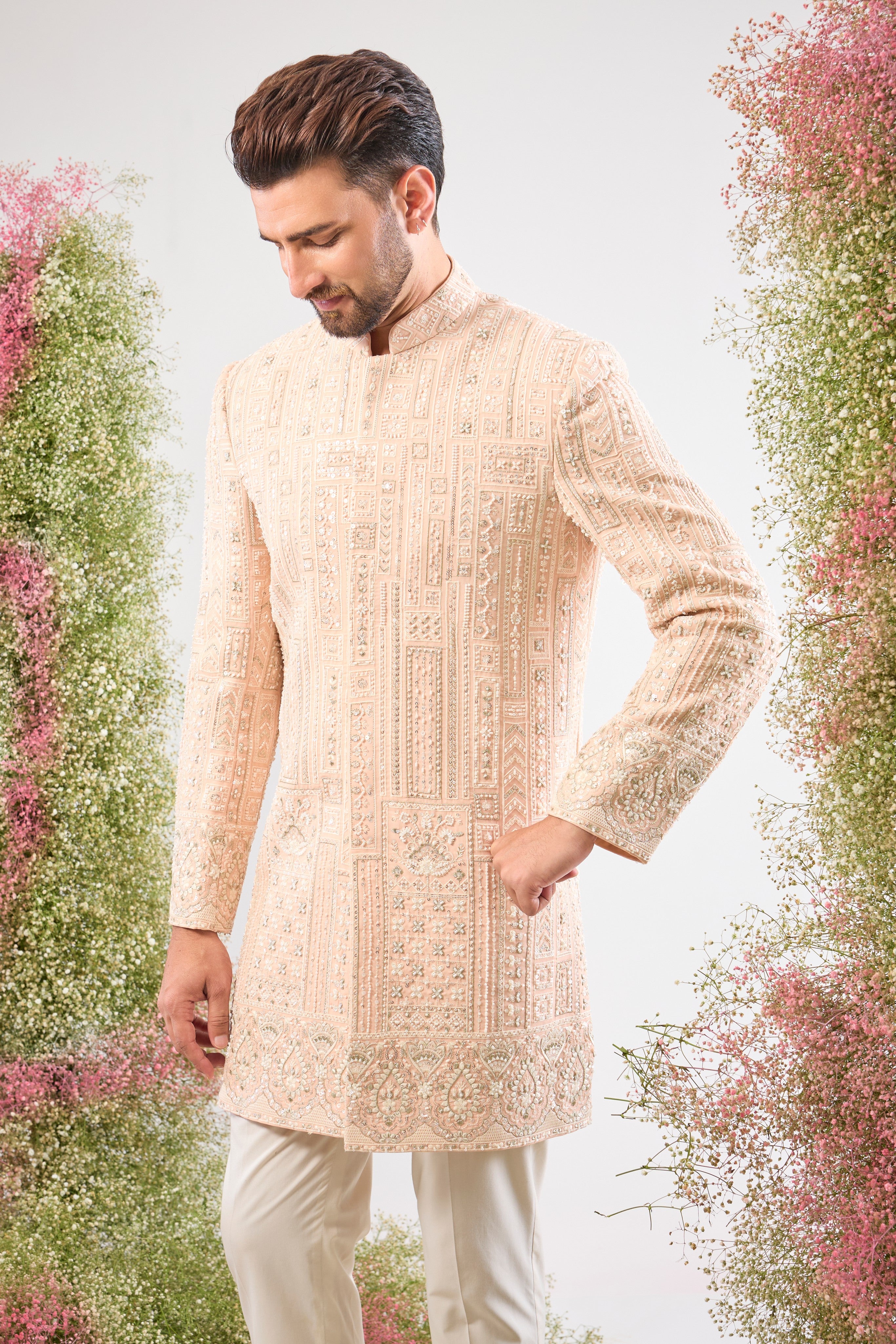 Our Pink Short Sherwani features a striking Geometrically Embroidered pattern, meticulously brought to life with exquisite Hand Work White Cut Dana and Sequin detailing.